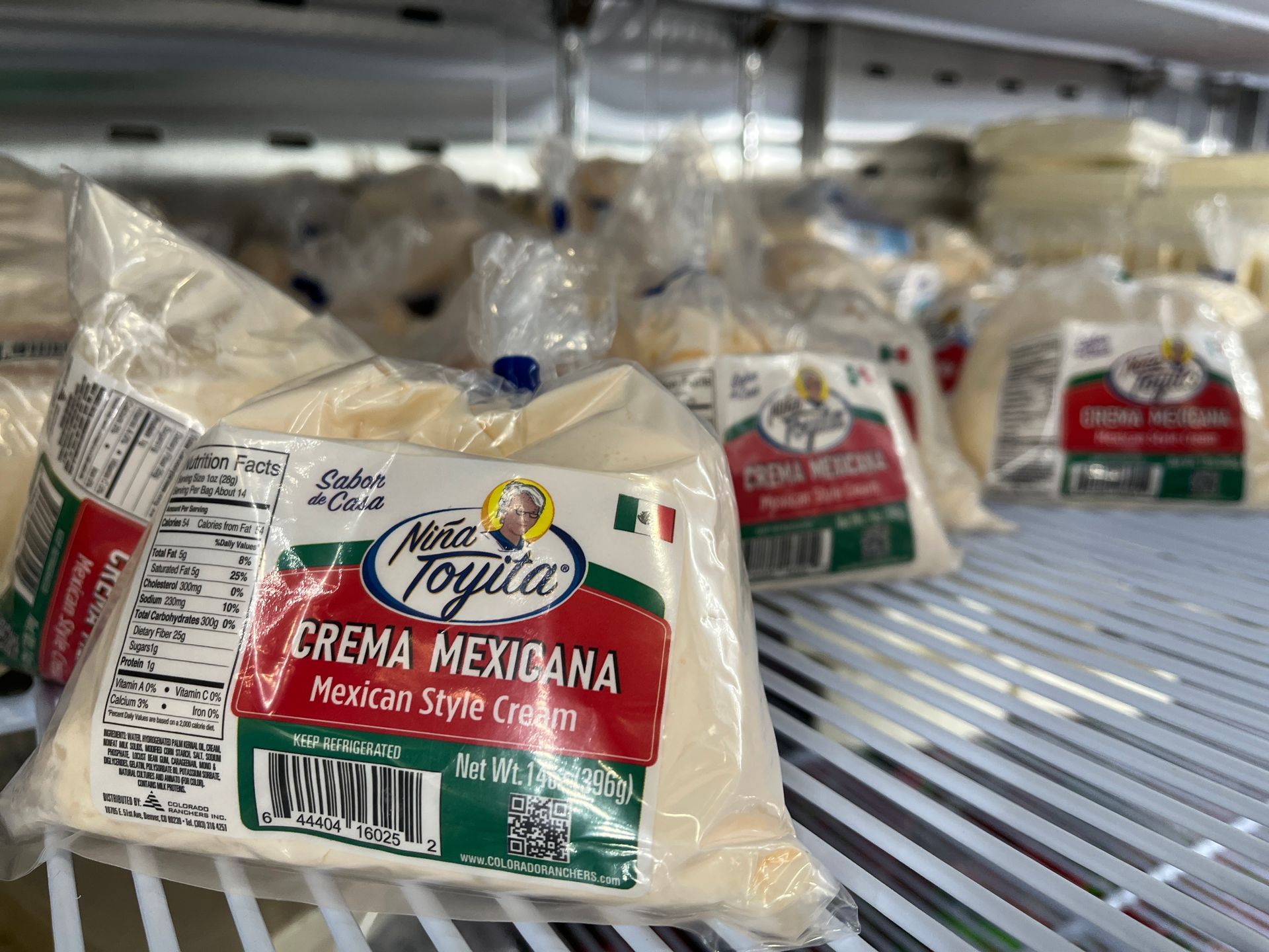 A refrigerator filled with bags of crema mexicana cheese.