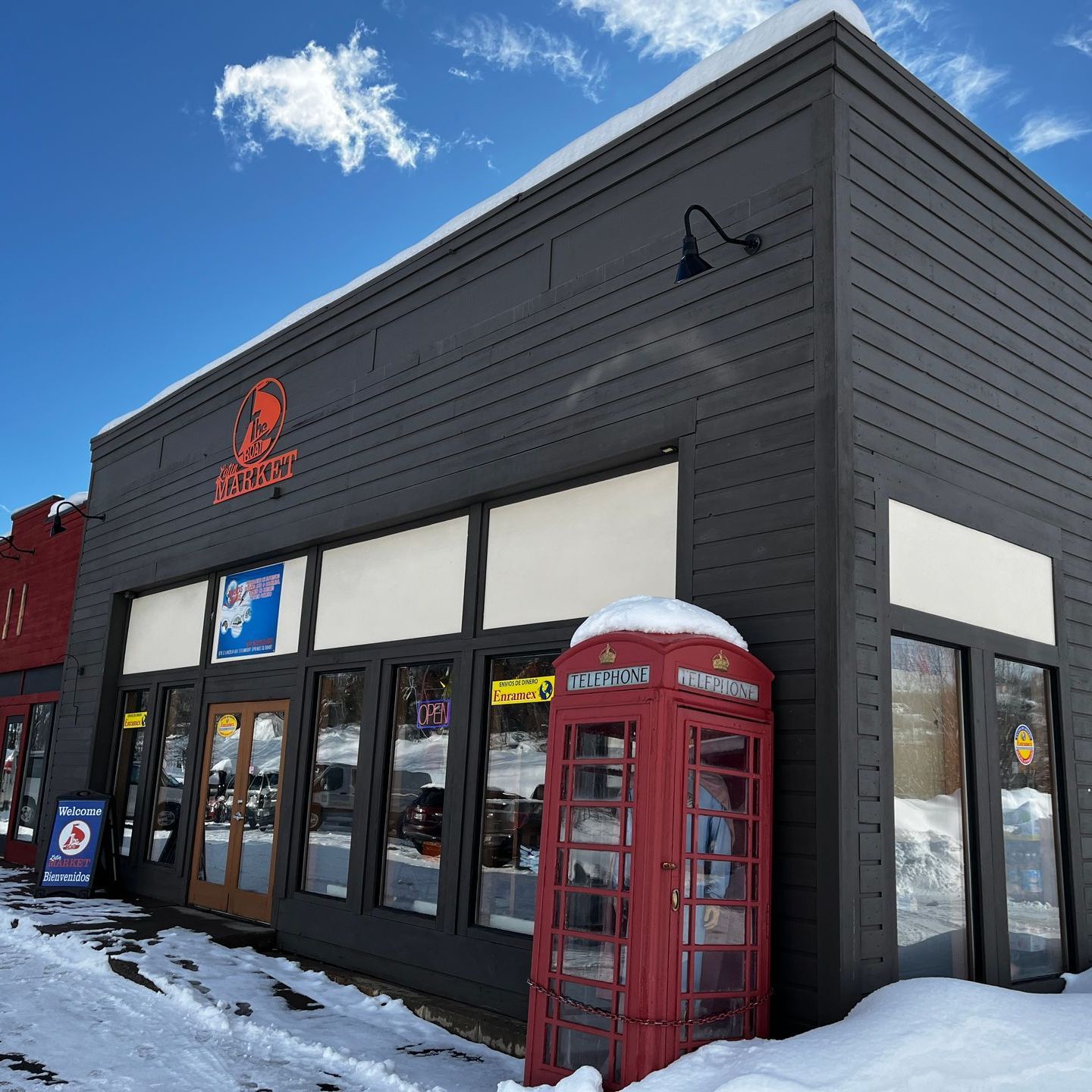 A black building with a red phone booth in front of it