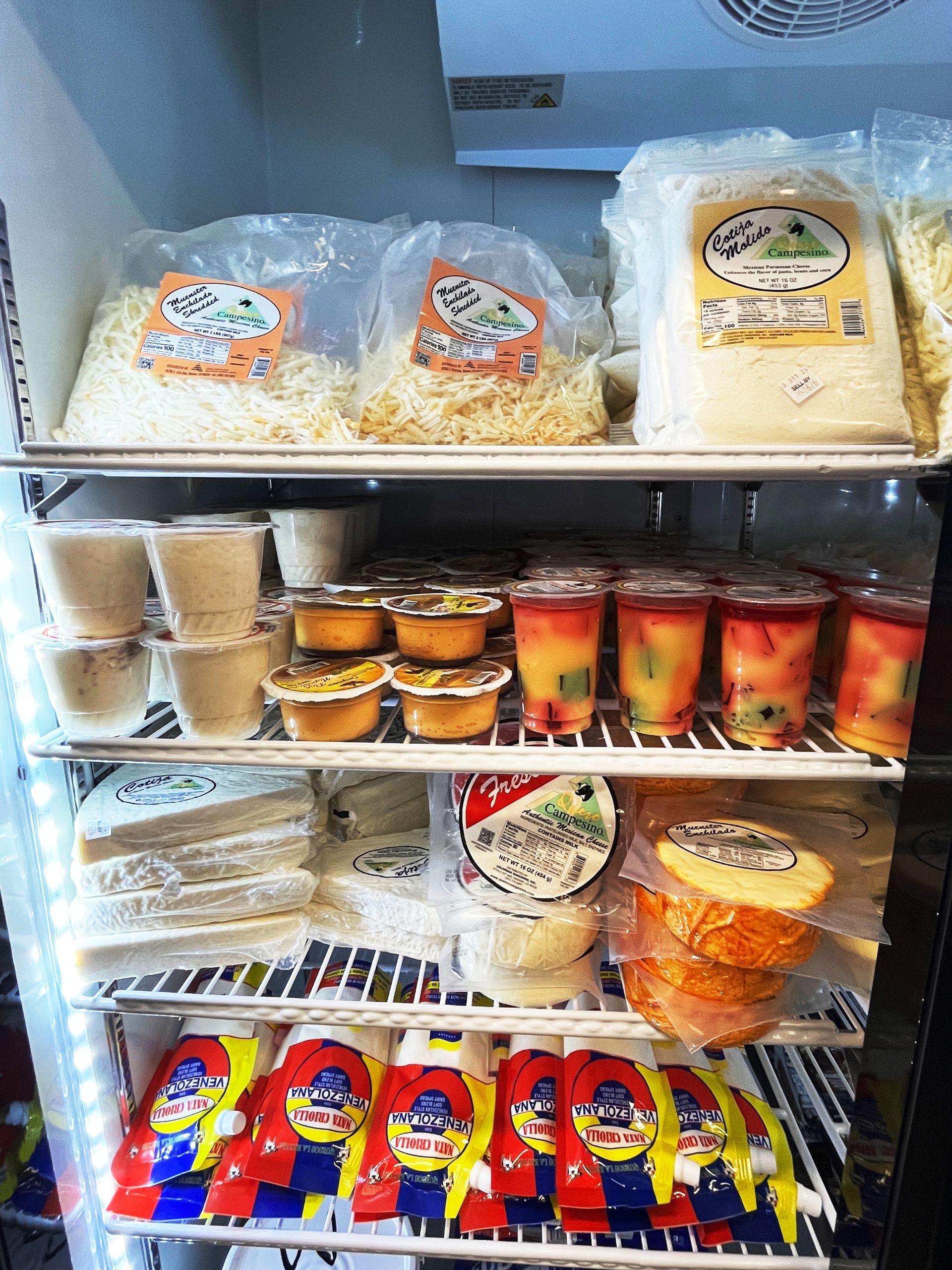 Refrigerator with various food items: cheese, pre-portioned cups, and snacks.