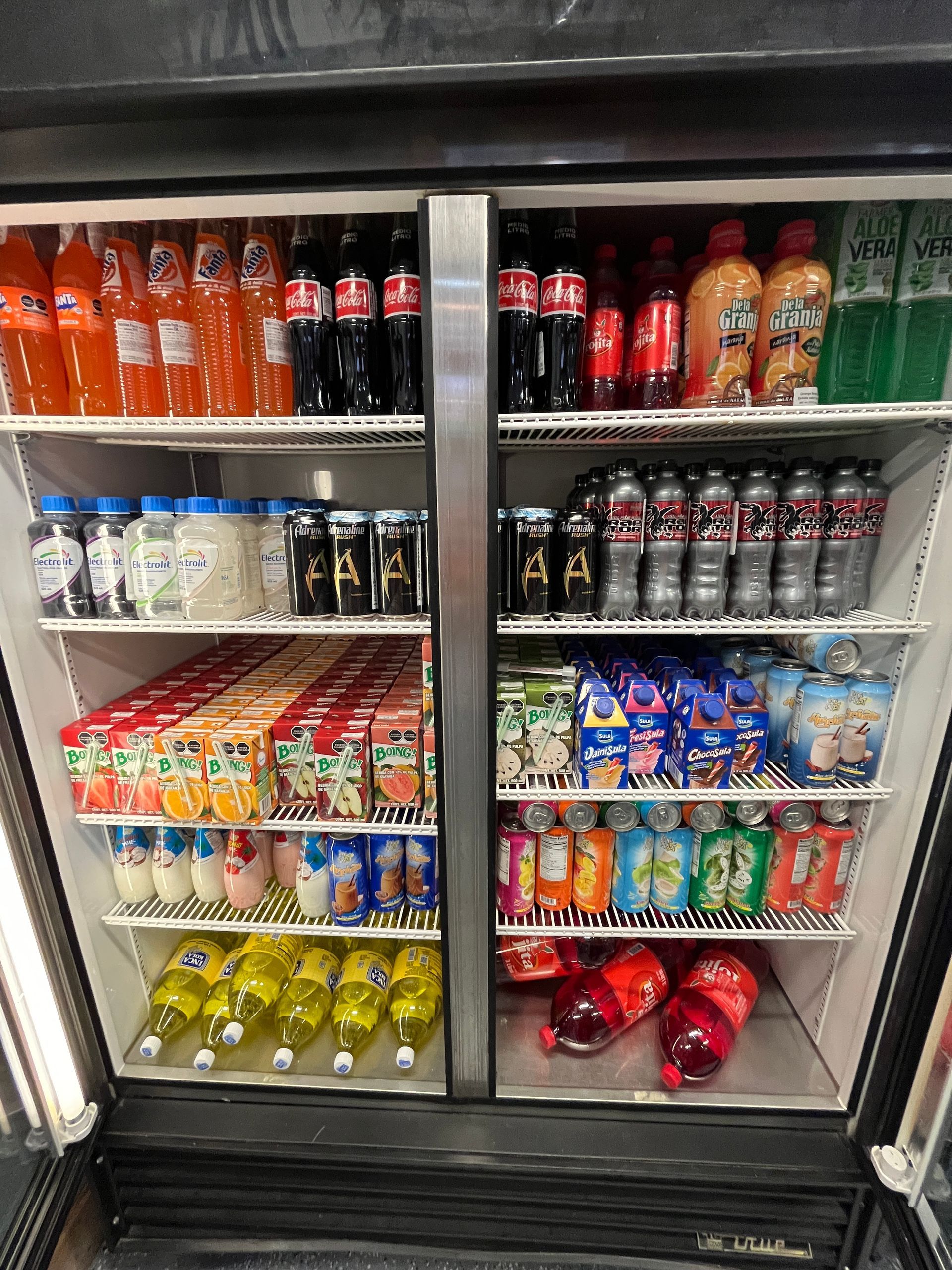 A refrigerated display case filled with various beverages like soda, juice, and water bottles.