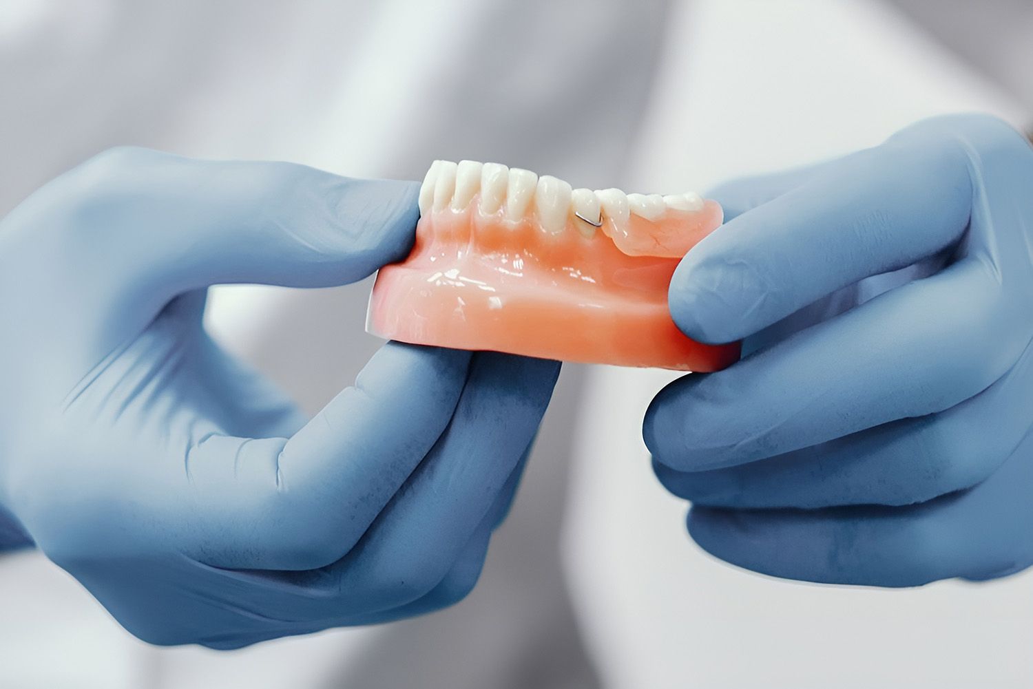 Hands In Blue Gloves Holding A Denture Model