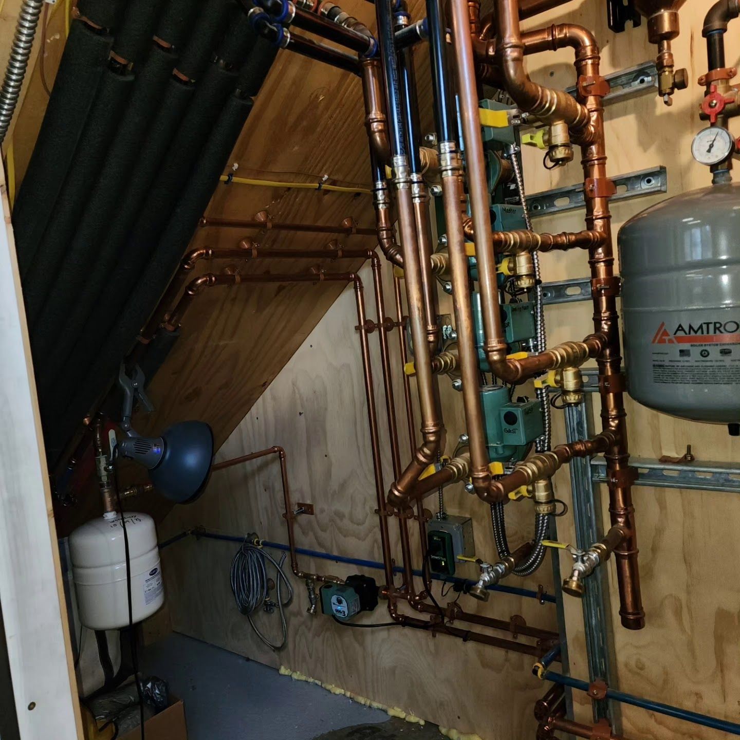 Copper pipes and heating system components installed on wooden wall.