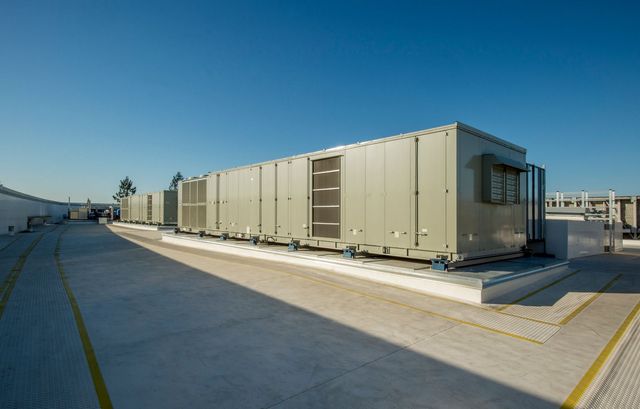 Exterior view of industrial air conditioning units on a rooftop under a clear blue sky.