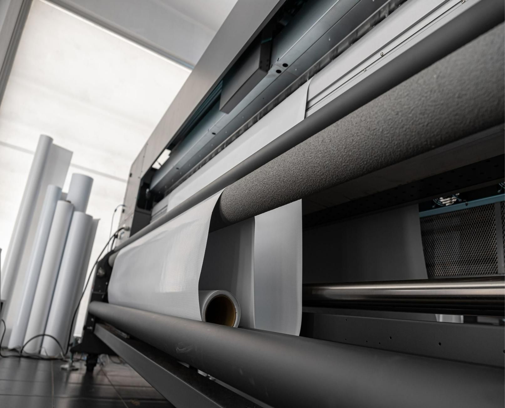 A Large Printing Machine Is Sitting In A Room With Rolls Of Paper On The Floor — Classic Design & Print in Svensson Heights, QLD