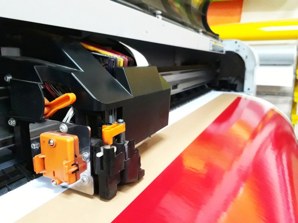 Close Up of a Machine That is Printing a Red Sheet of Paper — Classic Design & Print in Bundaberg, QLD