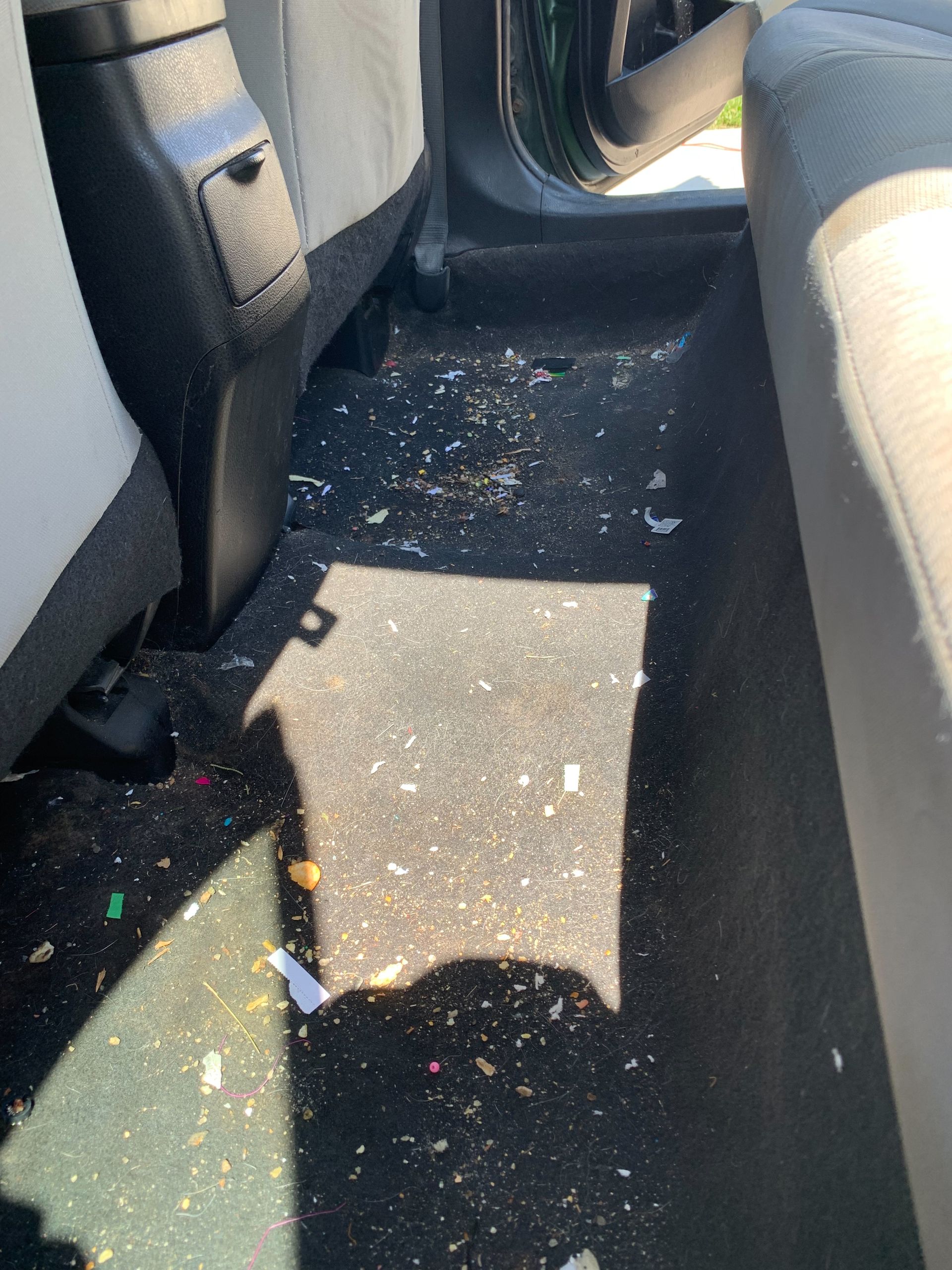 The inside of a car with a lot of trash on the floor.