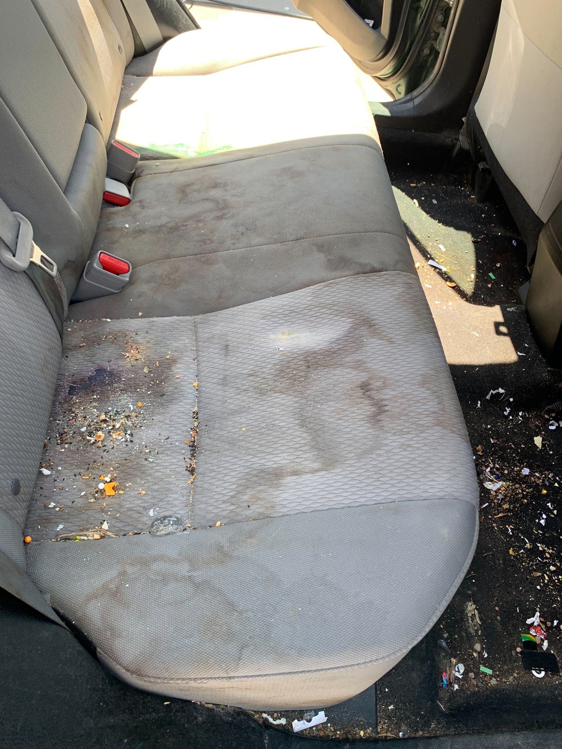 A dirty car seat with a lot of trash on it