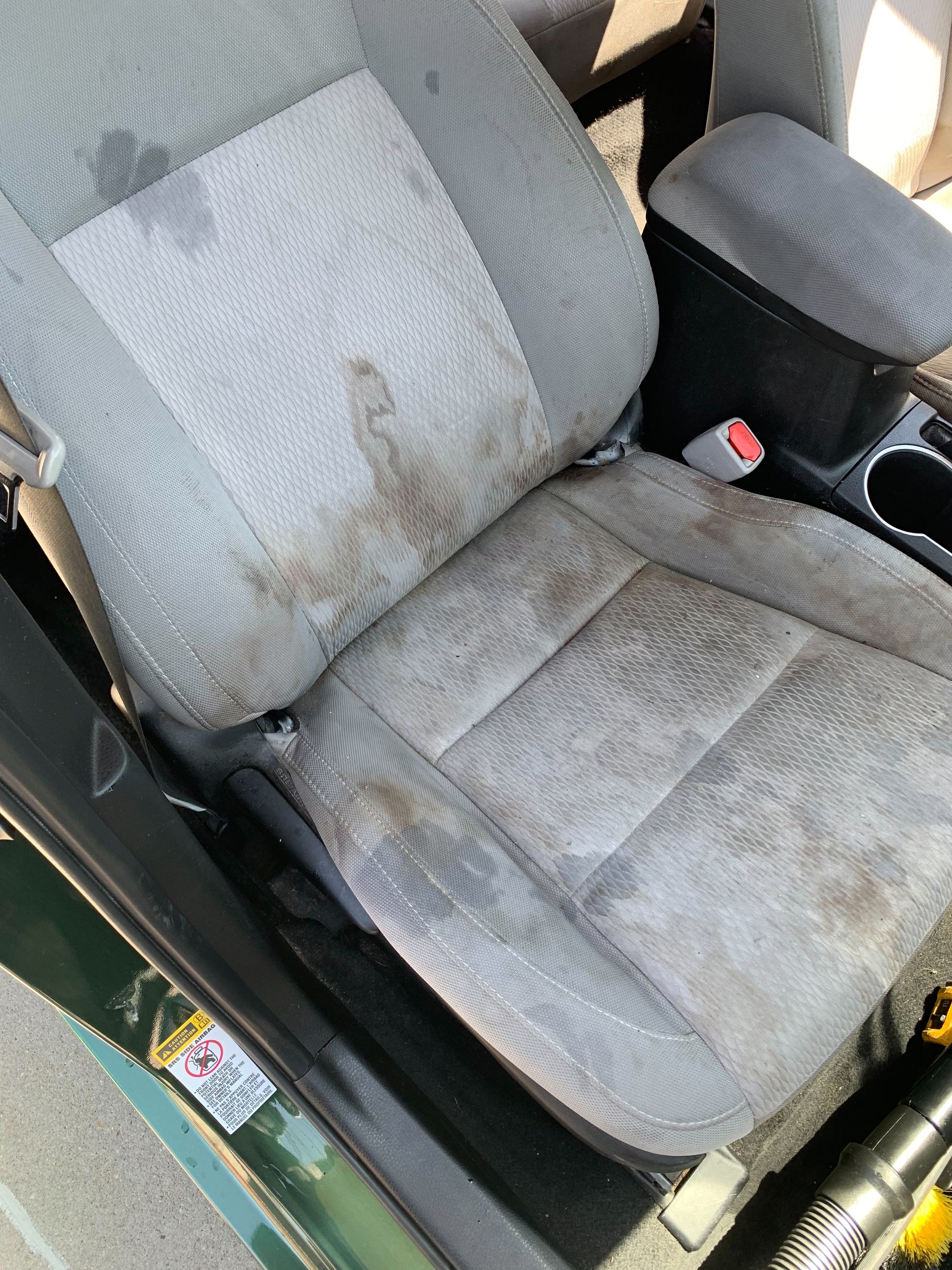 A dirty car seat is sitting in the trunk of a car.