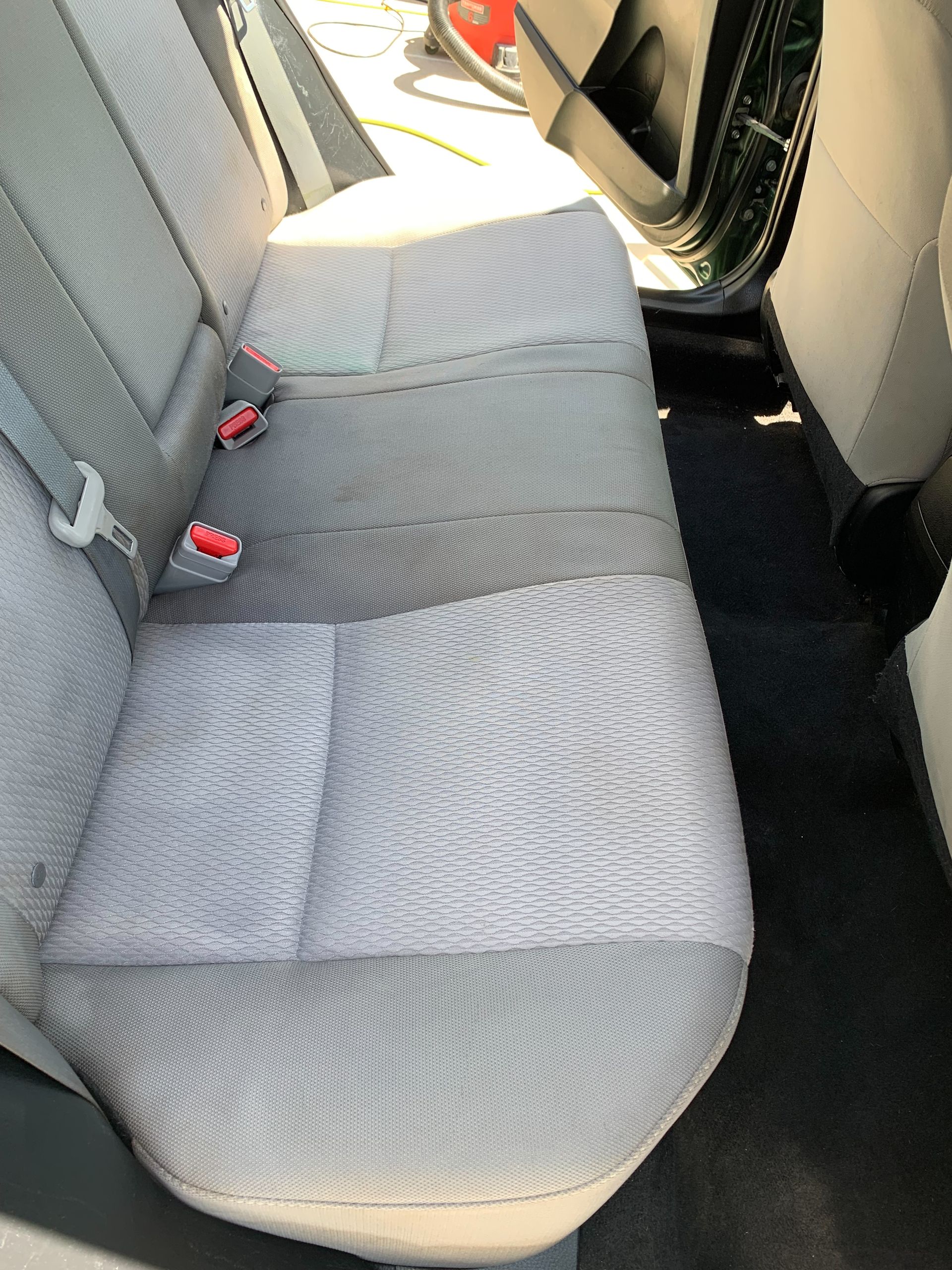 The back seat of a car with a seat belt on it.