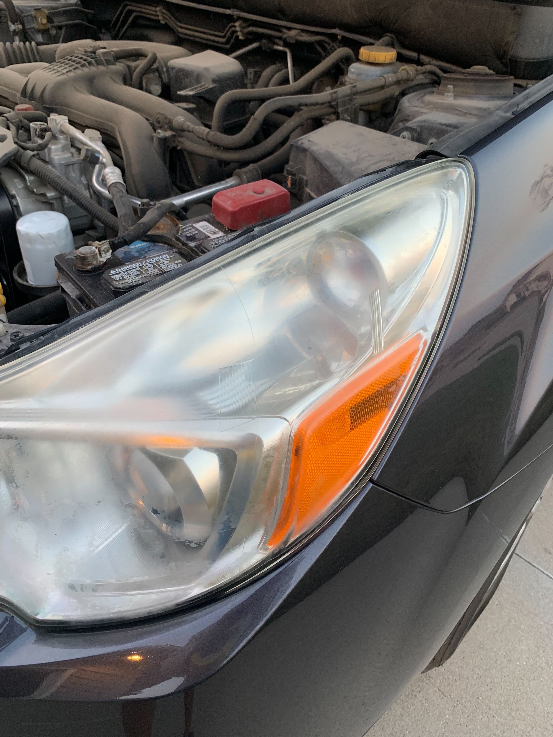 A close up of a car 's headlight with the hood open.