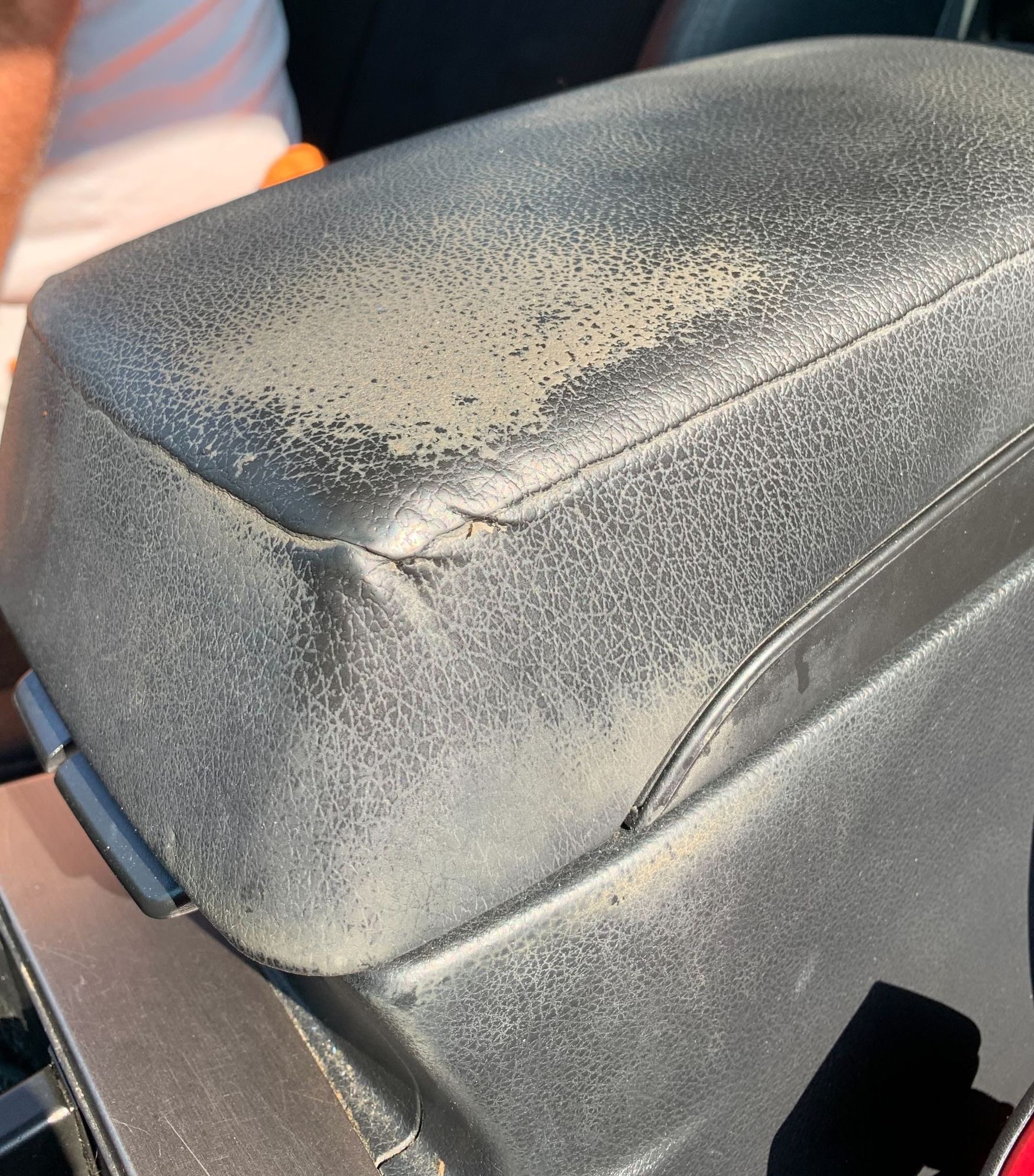 A close up of a black leather arm rest in a car