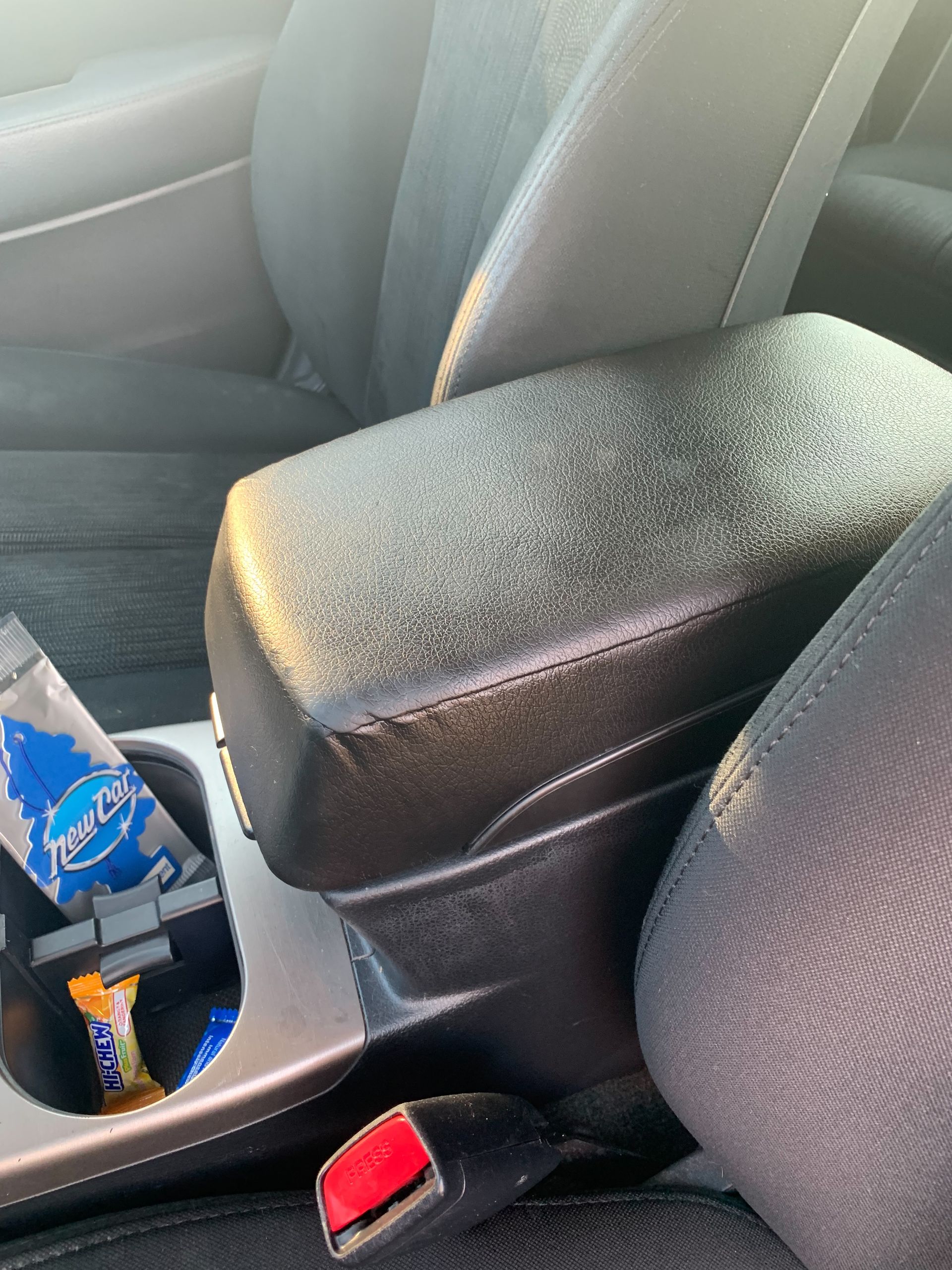 A car arm rest with a bag of pepsi in it