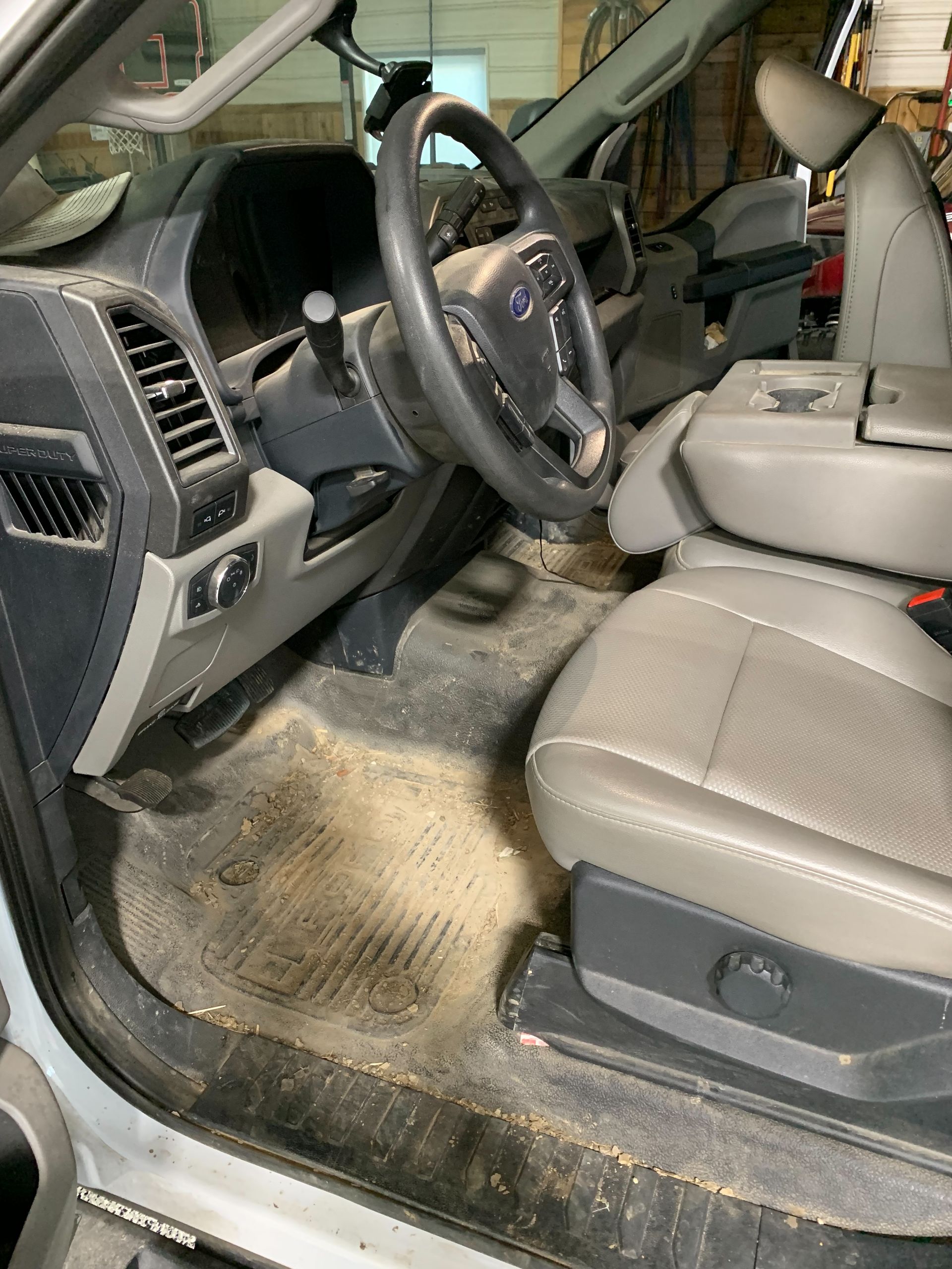 The inside of a dirty car with a steering wheel and seats.