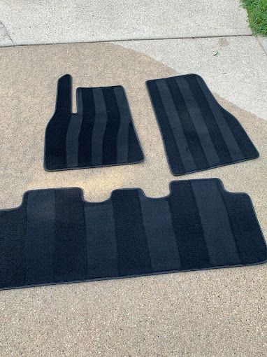 A set of black floor mats sitting on top of a sidewalk.