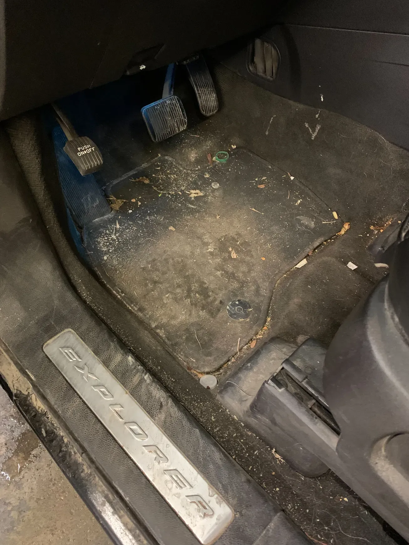 The inside of a dirty car with a stainless steel door sill.