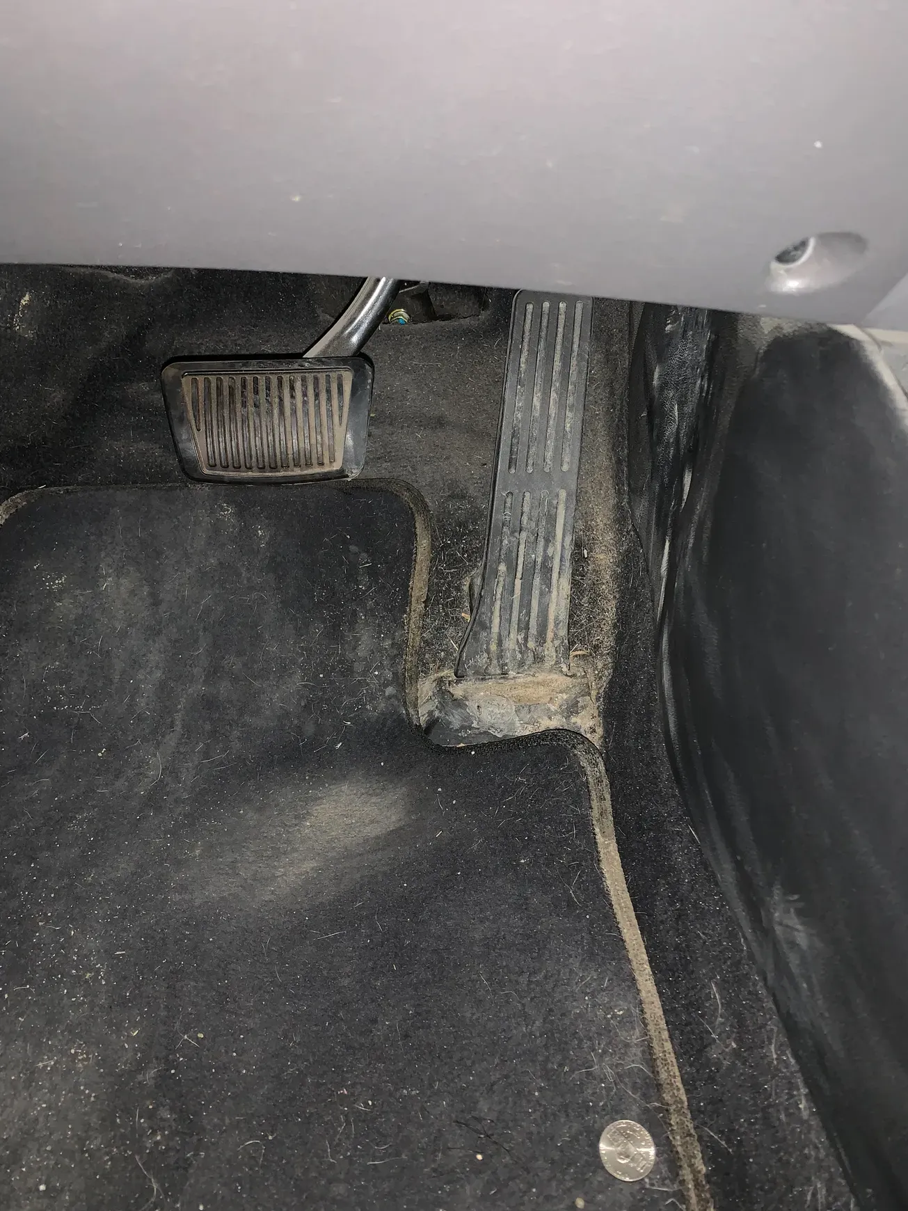 A close up of a dirty brake pedal in a car.
