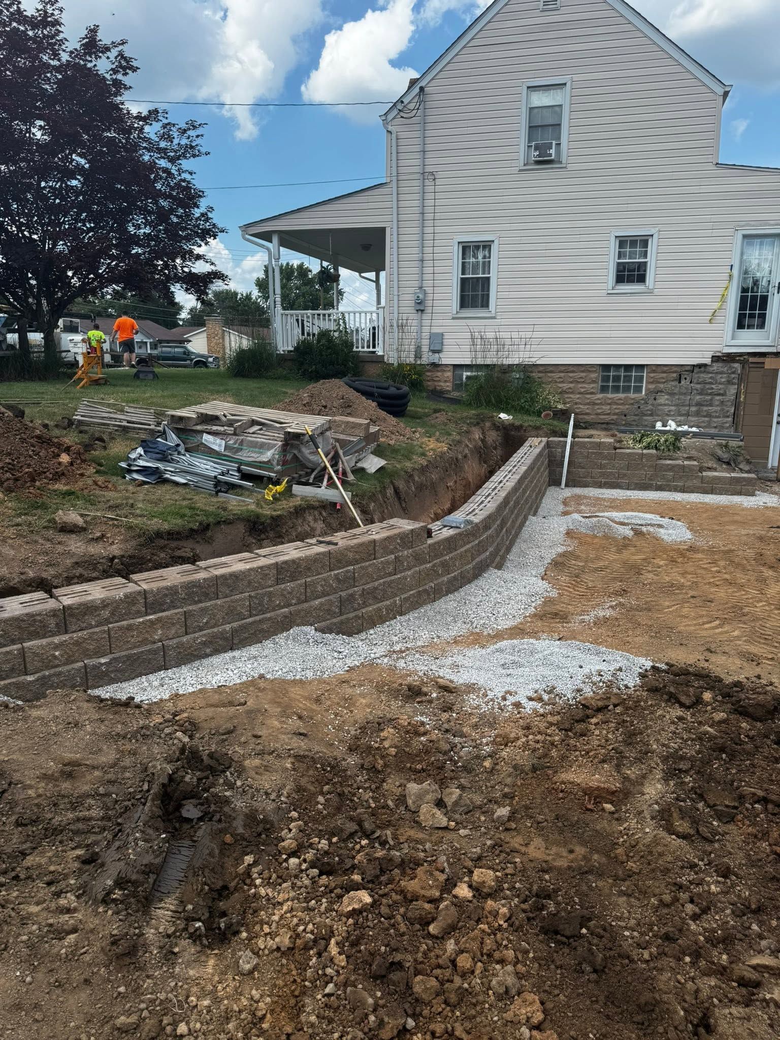 Backyard under renovation with gravel path, stone edging, and a white house in the background