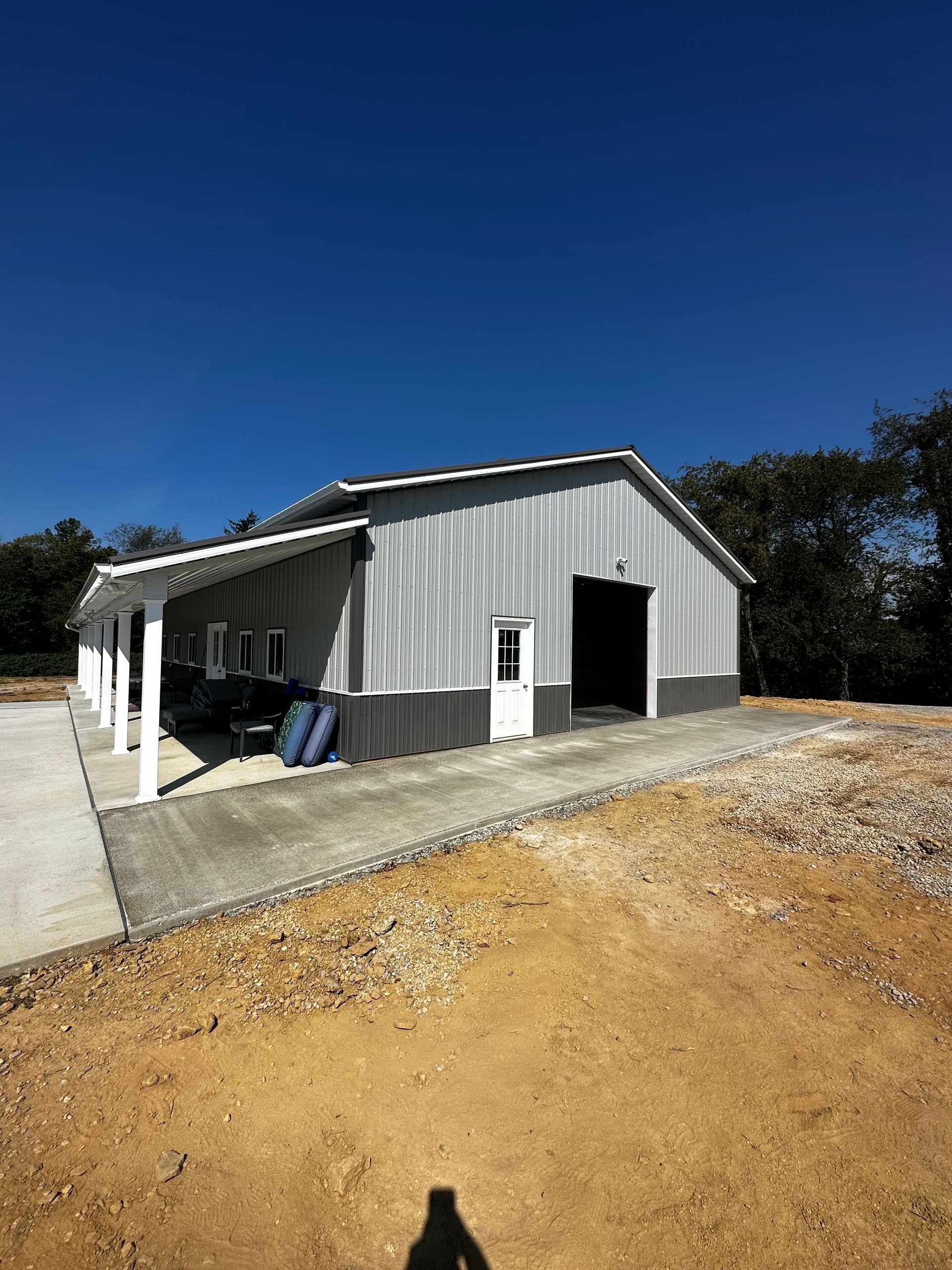 Small white metal shed with open doors on a gravel lot under a clear blue sky