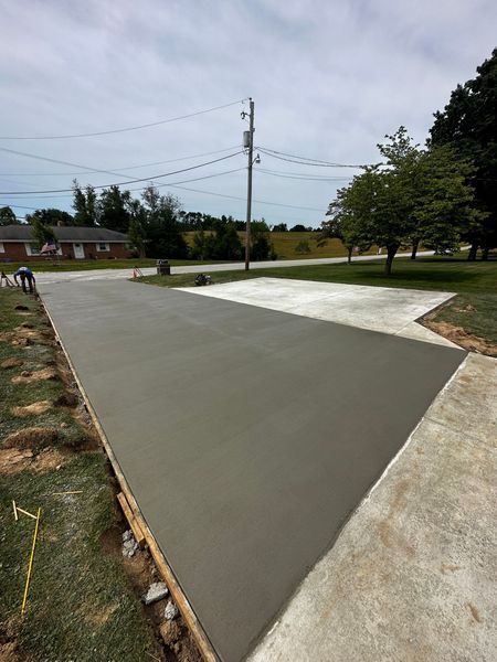 Freshly poured concrete driveway or slab beside an older concrete path in a suburban yard.