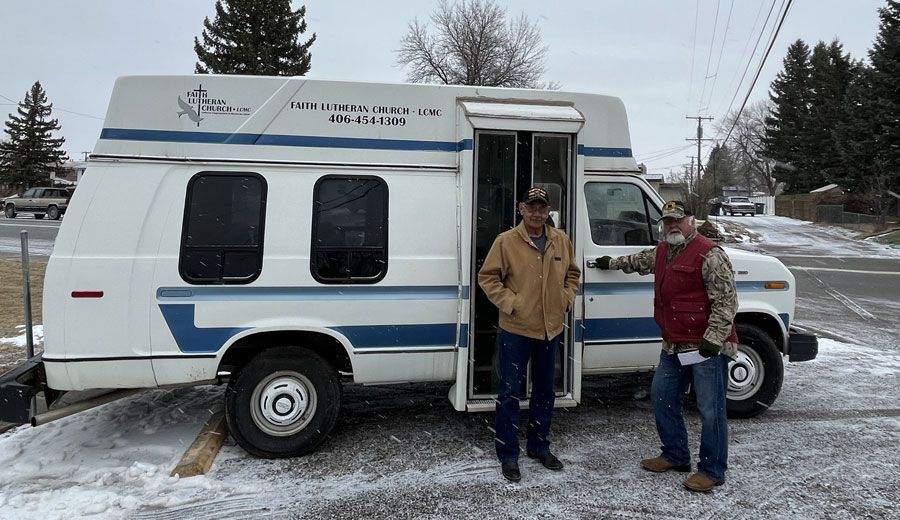 two men are standing in front of a white van with the door open