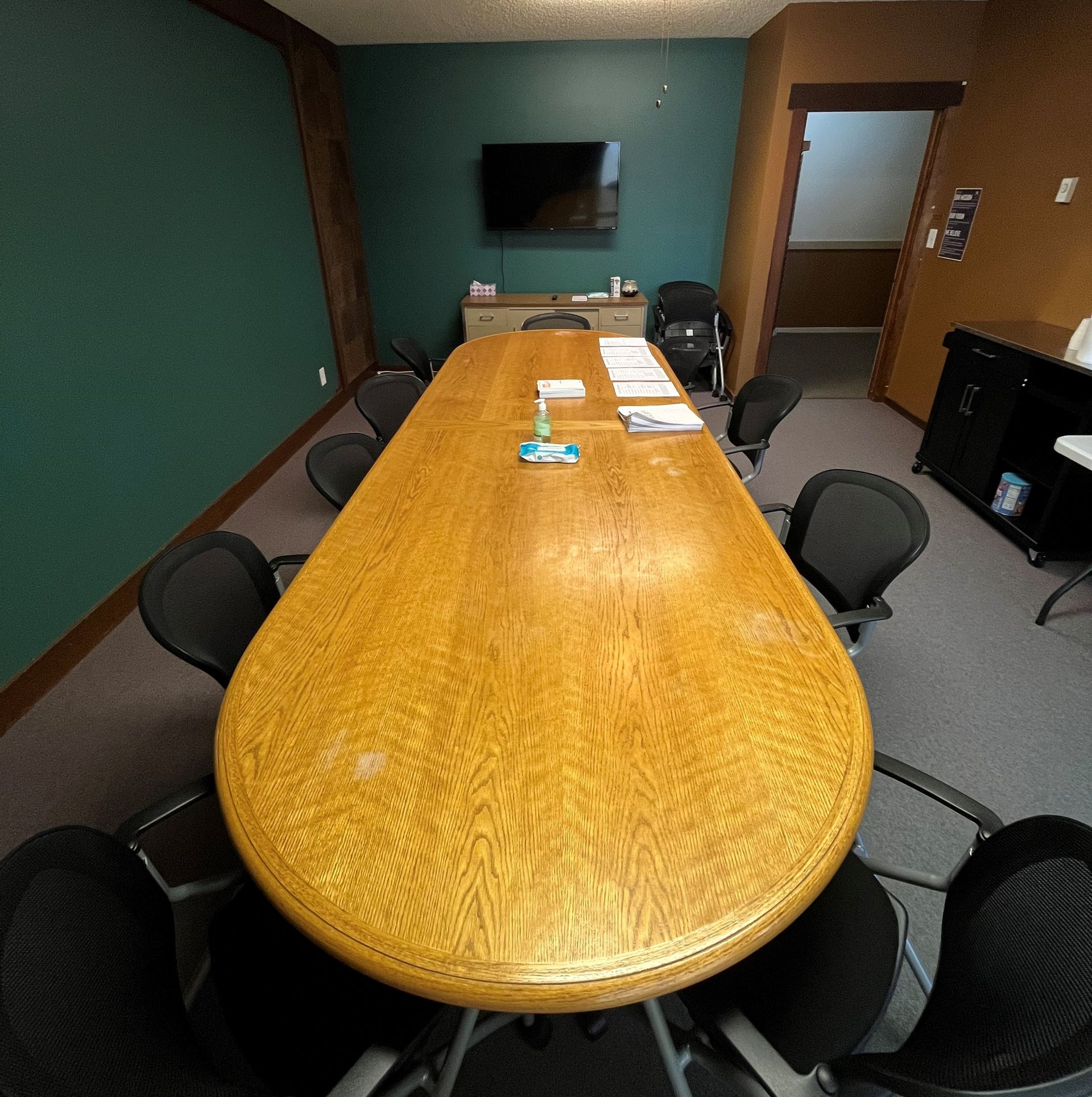 three people are standing in a room with a table and chairs .