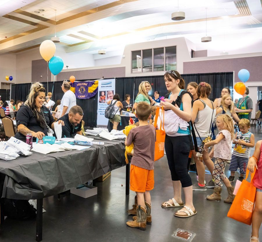 a group of people are standing around a table at a convention .