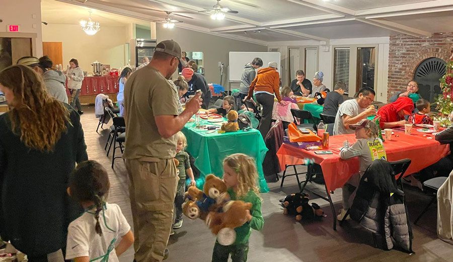 a group of people are standing around tables in a room .