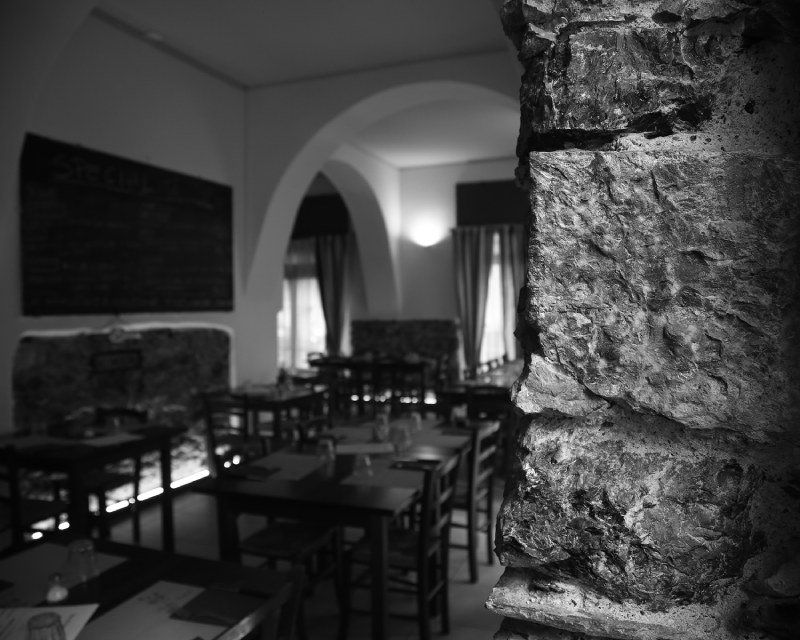 Una foto in bianco e nero di un ristorante con tavoli e sedie