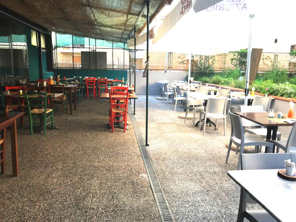 Un ristorante con tavoli e sedie e un ombrellone con scritto malta