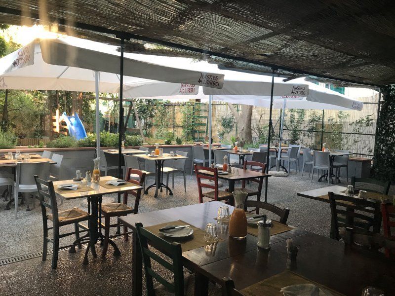Un ristorante pieno di tavoli e sedie sotto gli ombrelloni.