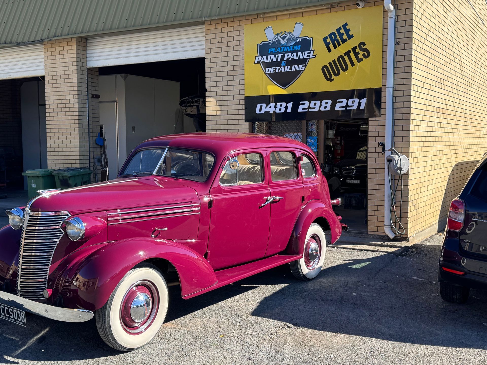 A White Car Is Parked In Front Of A Garage Door — Platinum Paint & Panel Southport In Southport, QLD