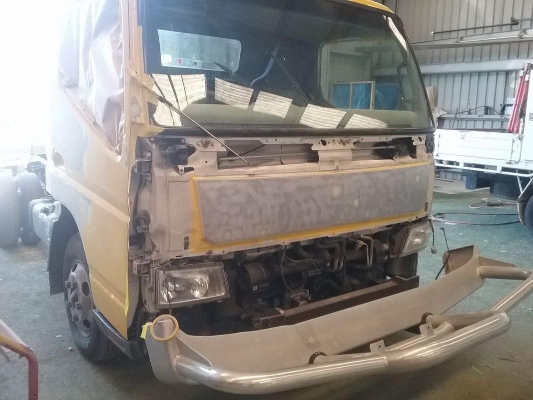 A Yellow Truck Is Being Repaired In A Garage — Platinum Paint & Panel Southport In Southport, QLD