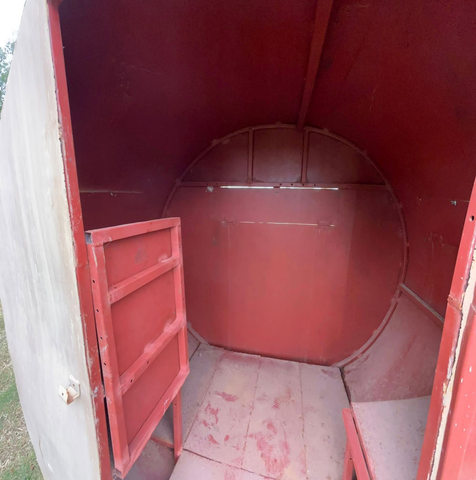 Red cylindrical metal tank interior with an open hatch and red-painted door panel.