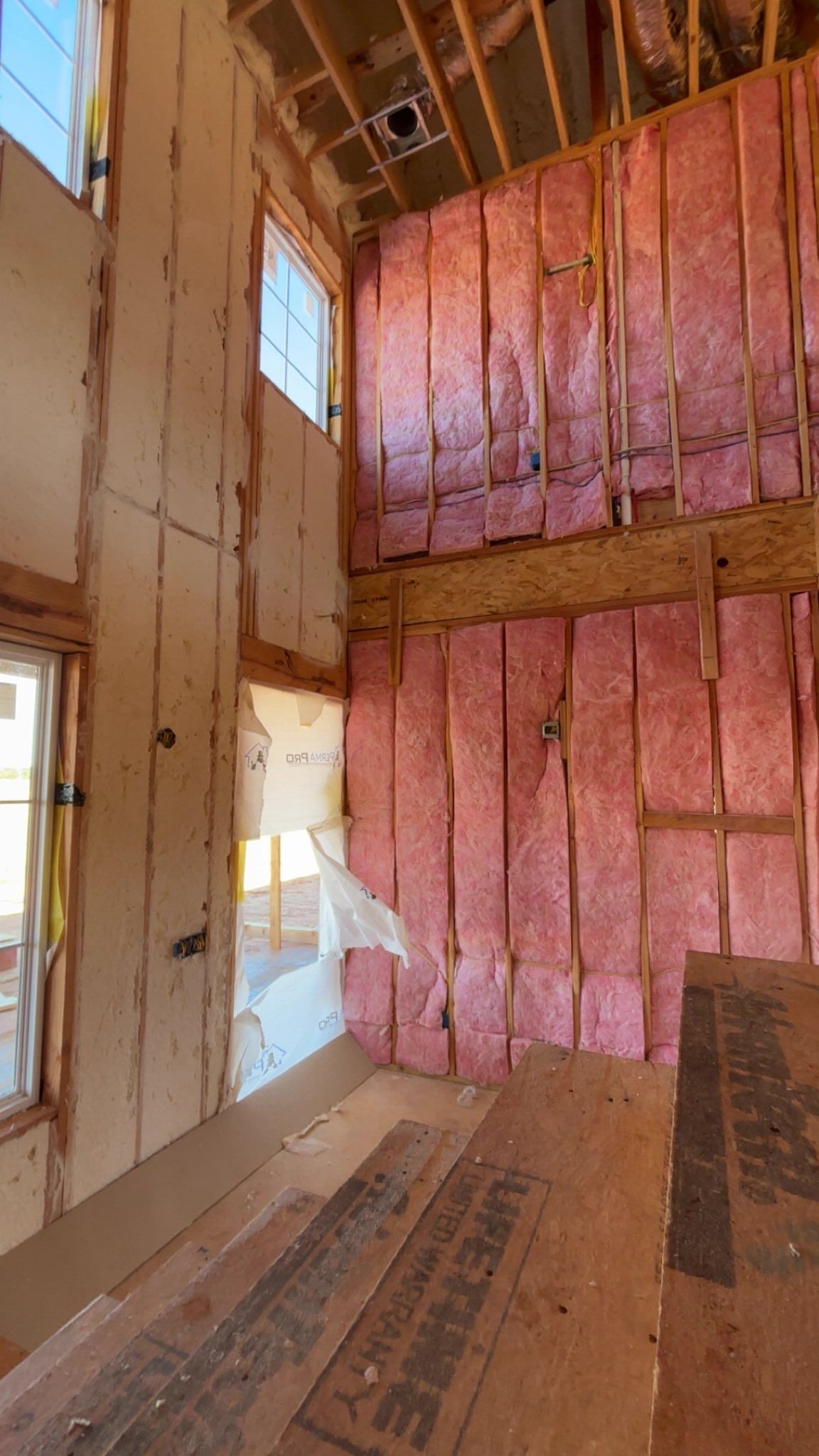 Interior wall framing with pink insulation and exposed wood studs in an unfinished room