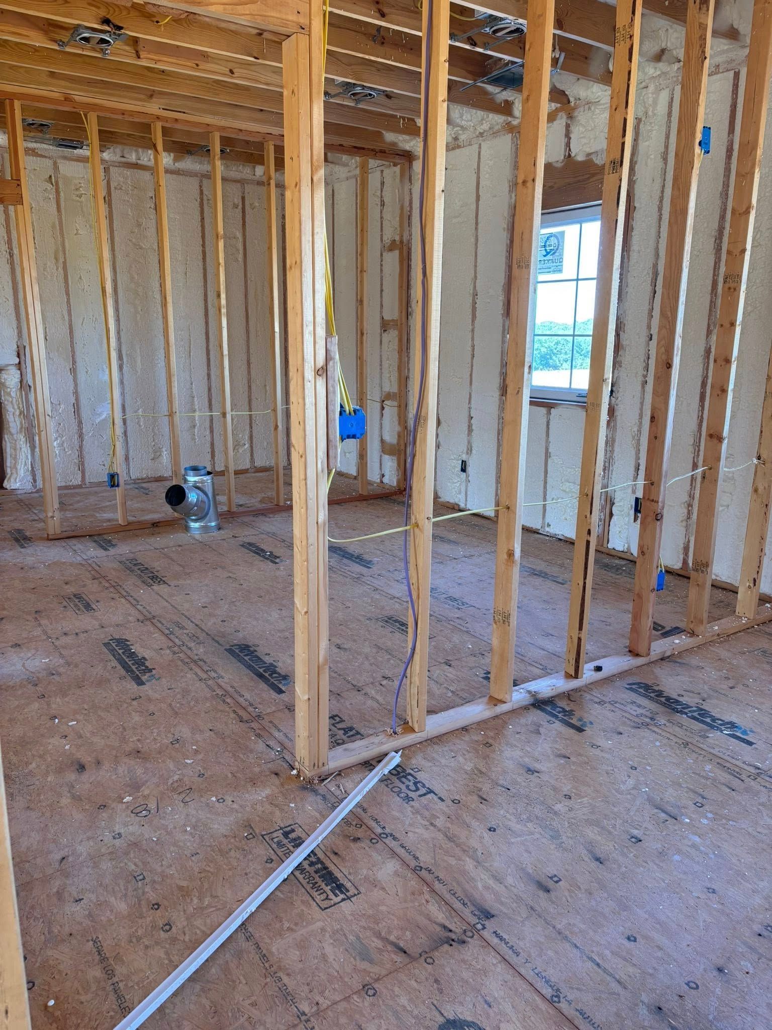 Unfinished house interior with exposed wooden framing, subfloor, and electrical conduit.