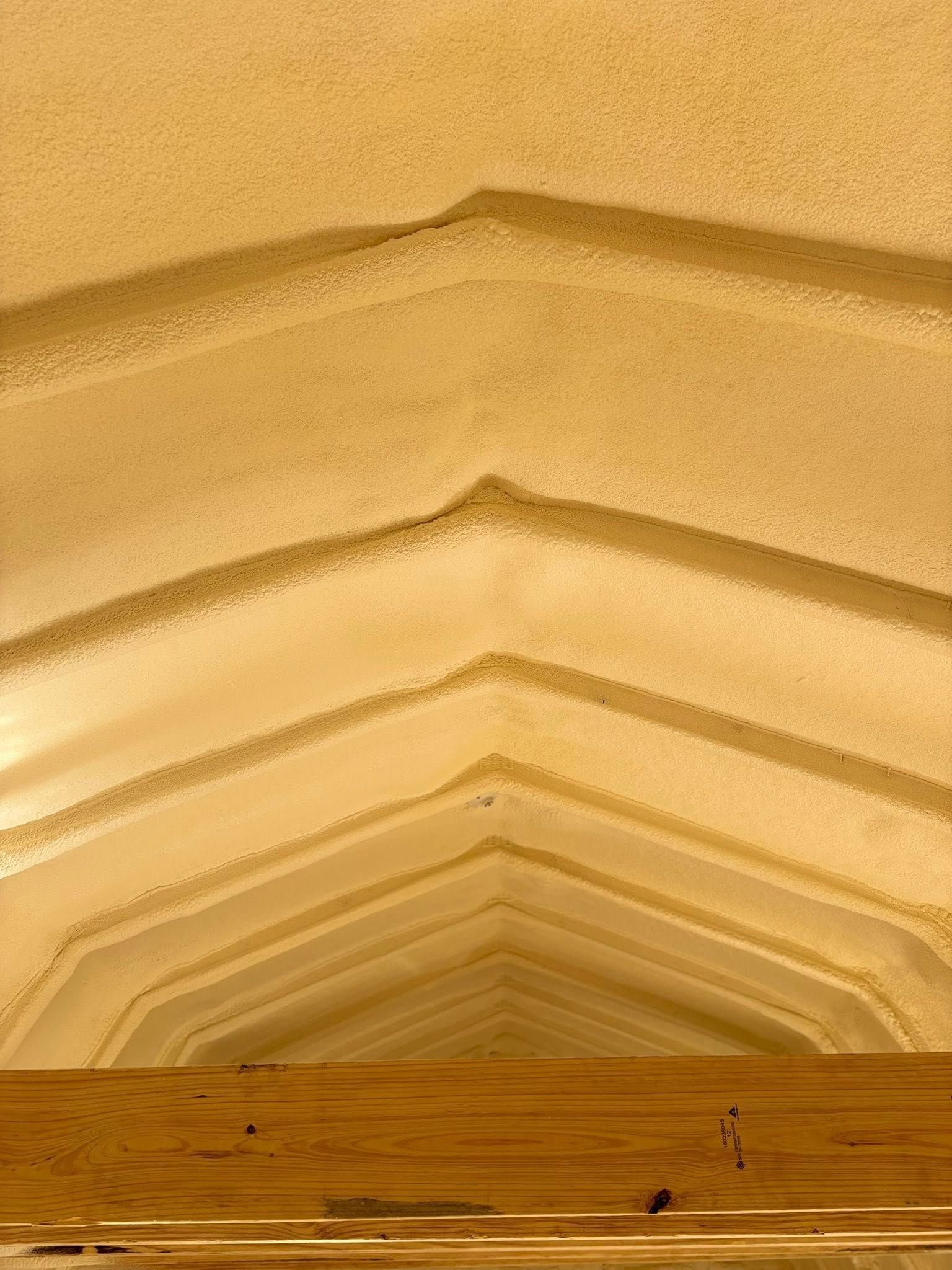 Symmetrical beige vaulted ceiling with repeating arches and a few tiny people at the bottom