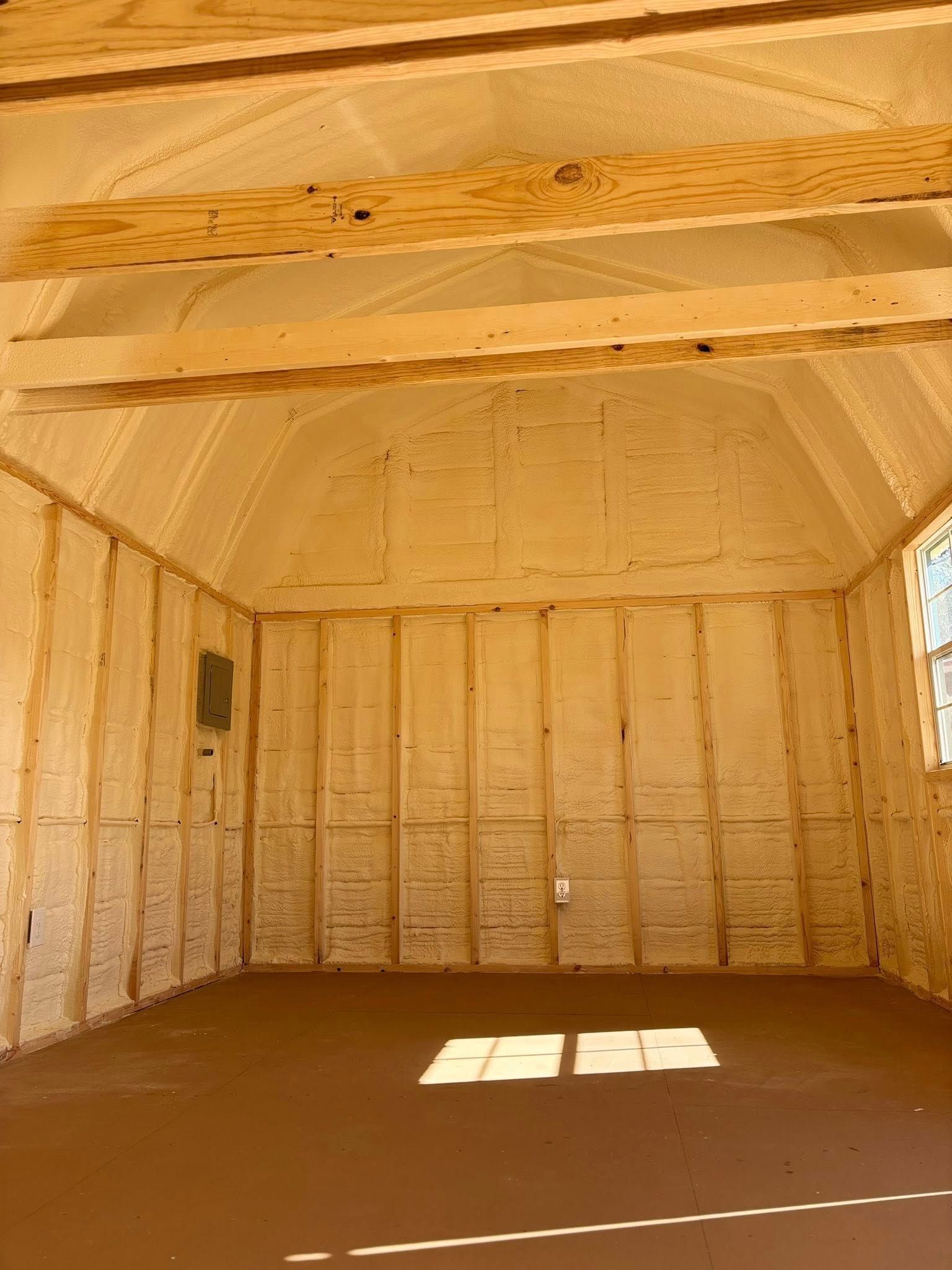 Empty unfinished shed interior with exposed wood framing and sunlit floor patch