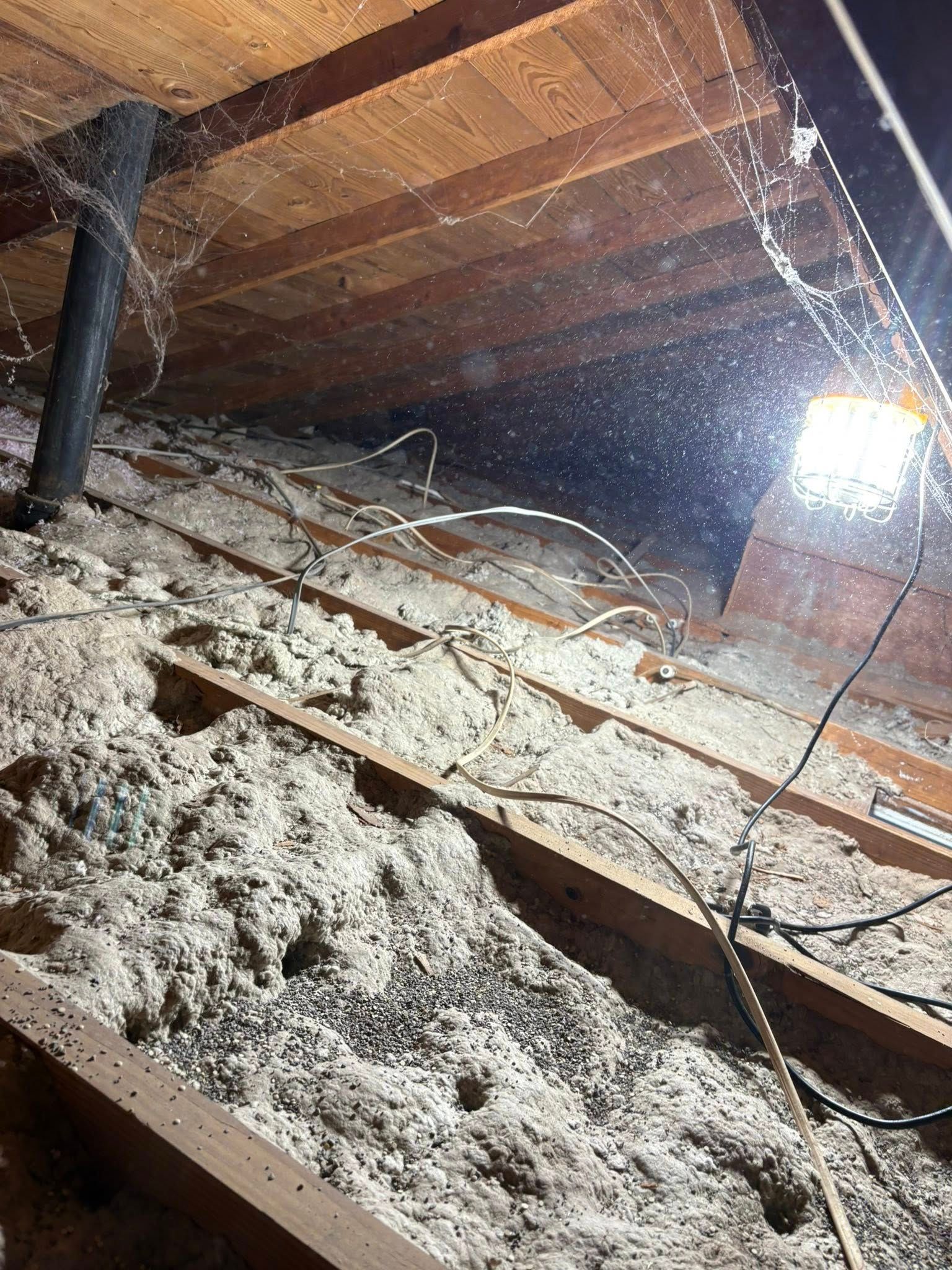 Snow-covered attic with exposed beams and bright sunlight shining through a window