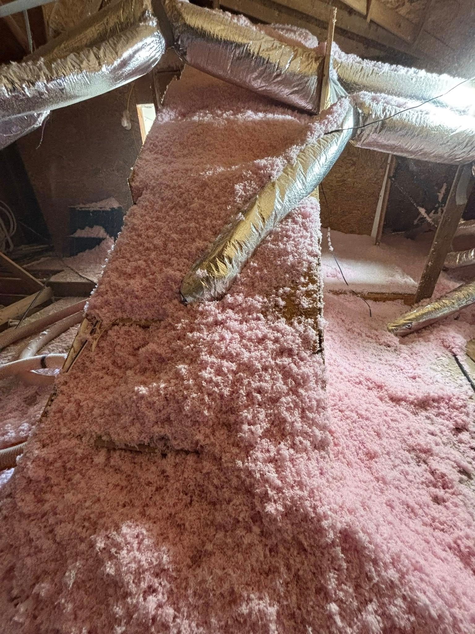 A large pile of pink granular material spills across the floor under a wooden structure.