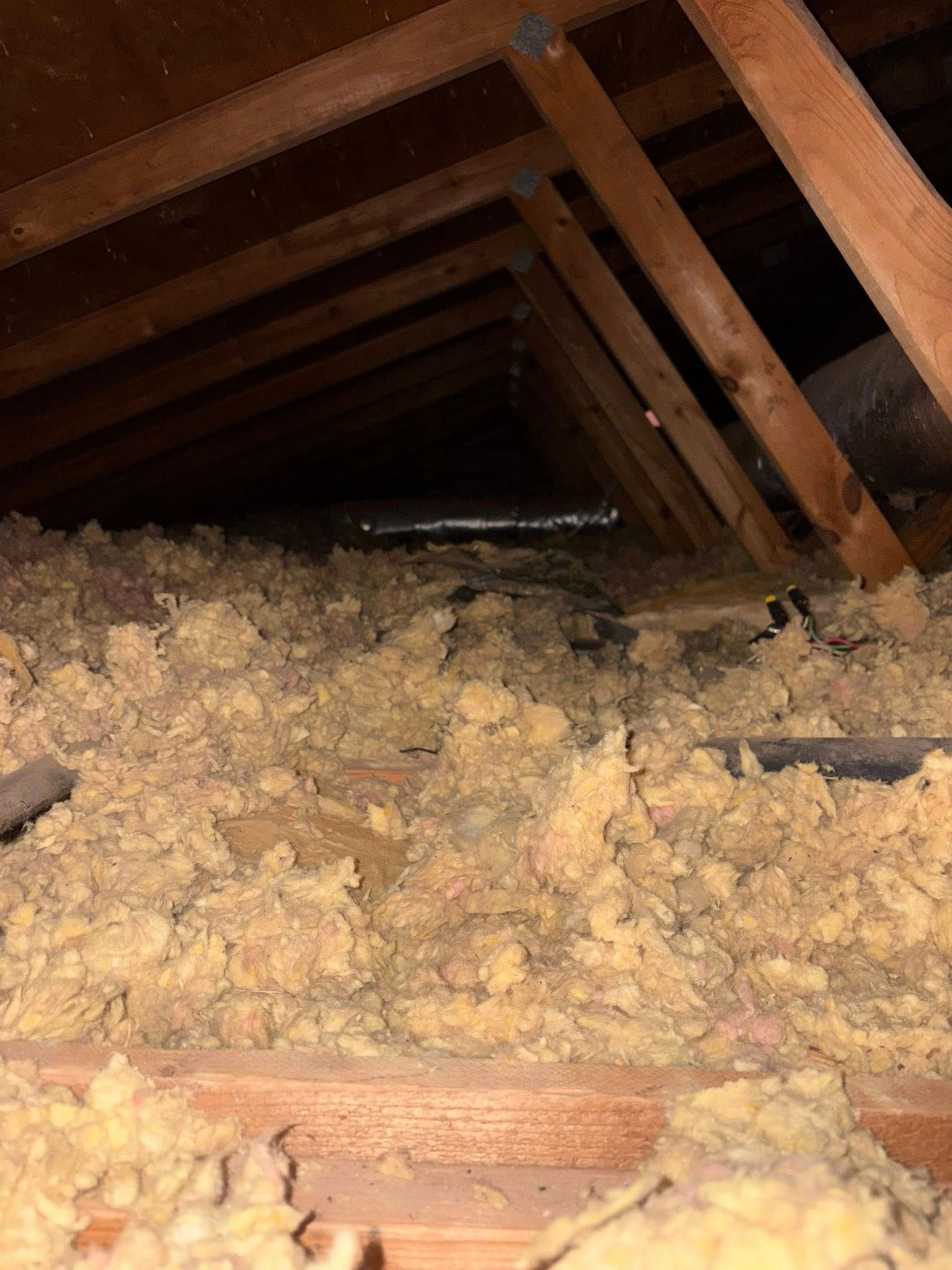 Attic with exposed rafters and thick piles of blown-in insulation