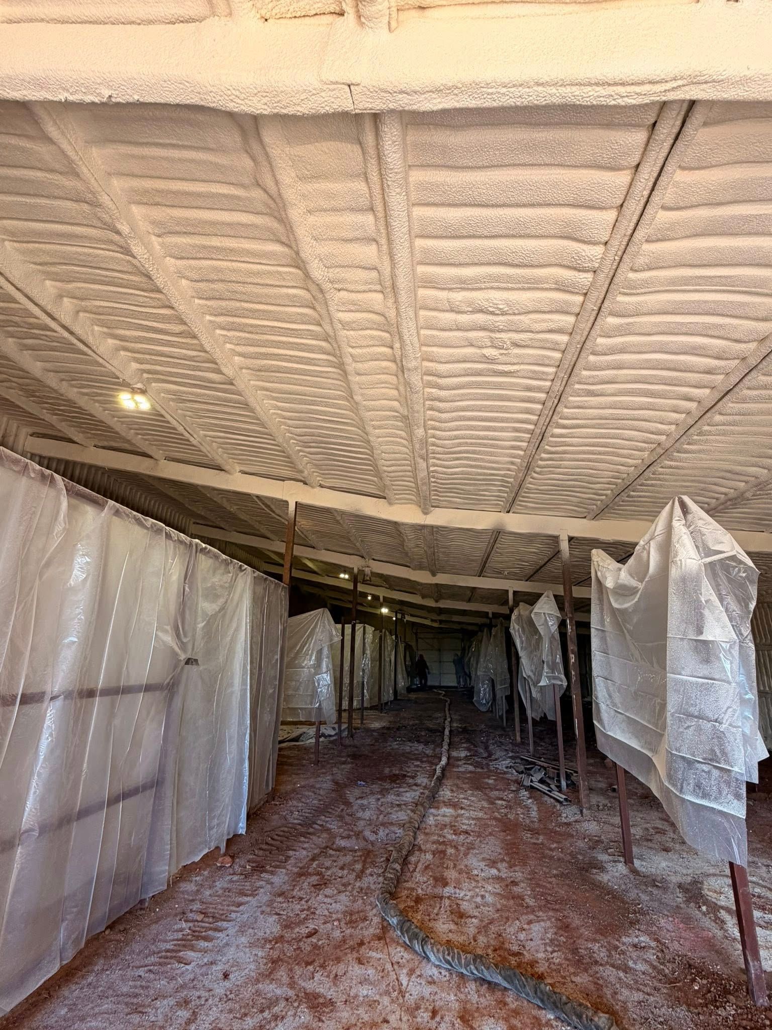 Narrow fabric-lined corridor with white plastic sheeting and a textured ceiling under construction