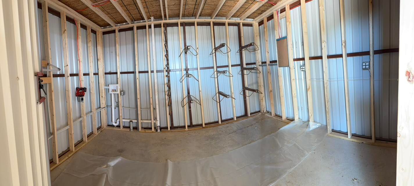 Unfinished room with exposed wood framing, insulation, and plastic-covered floor under construction