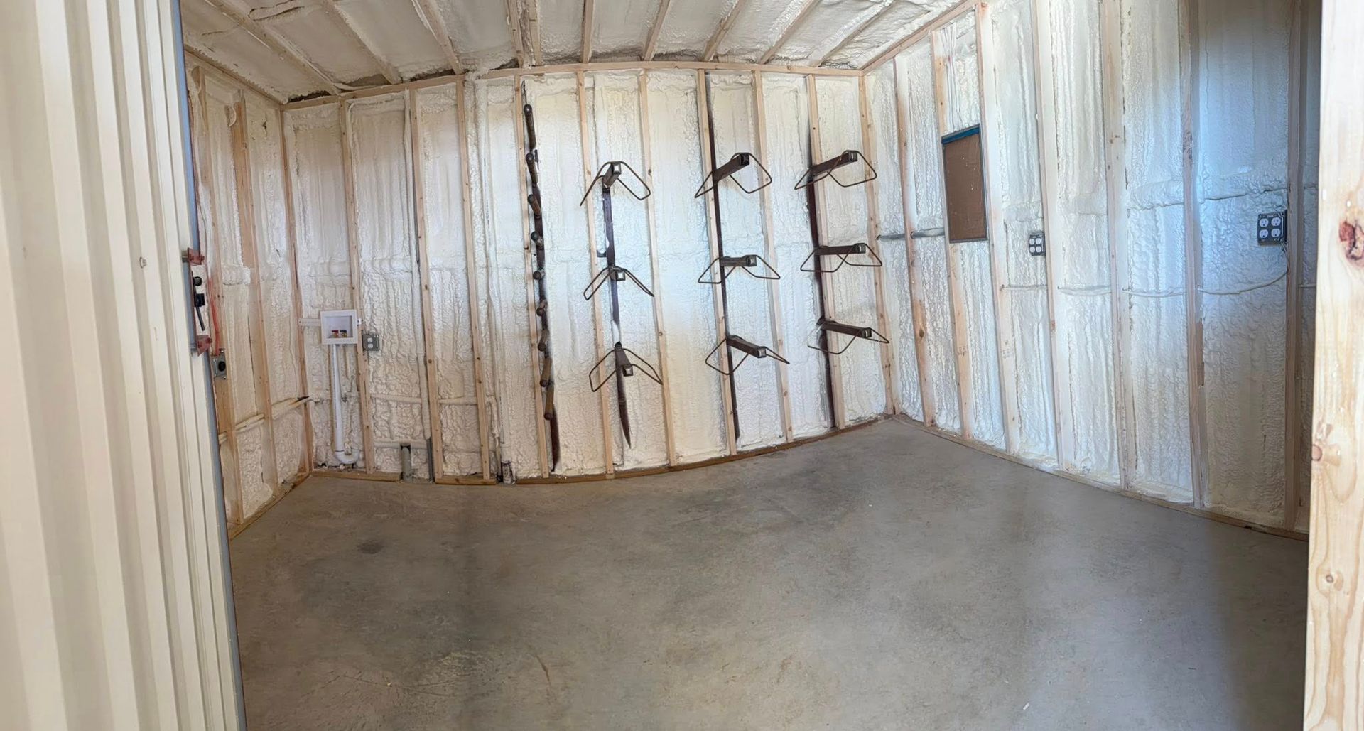 Empty room with white insulated walls and a bare concrete floor