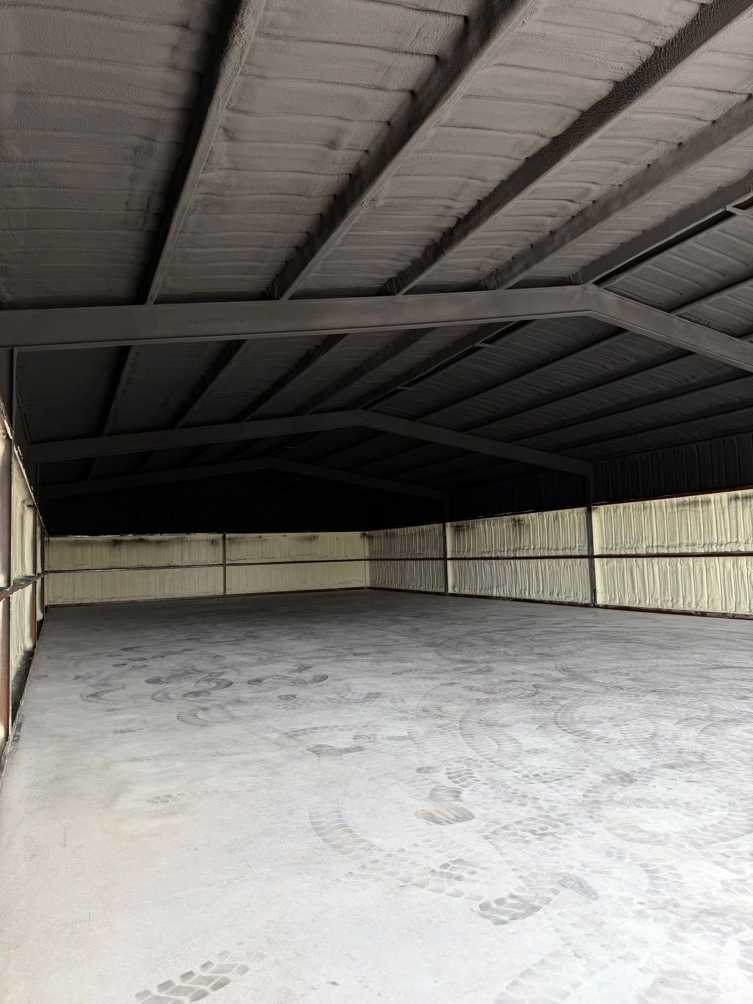 Empty covered storage shed with a corrugated metal roof and concrete floor.