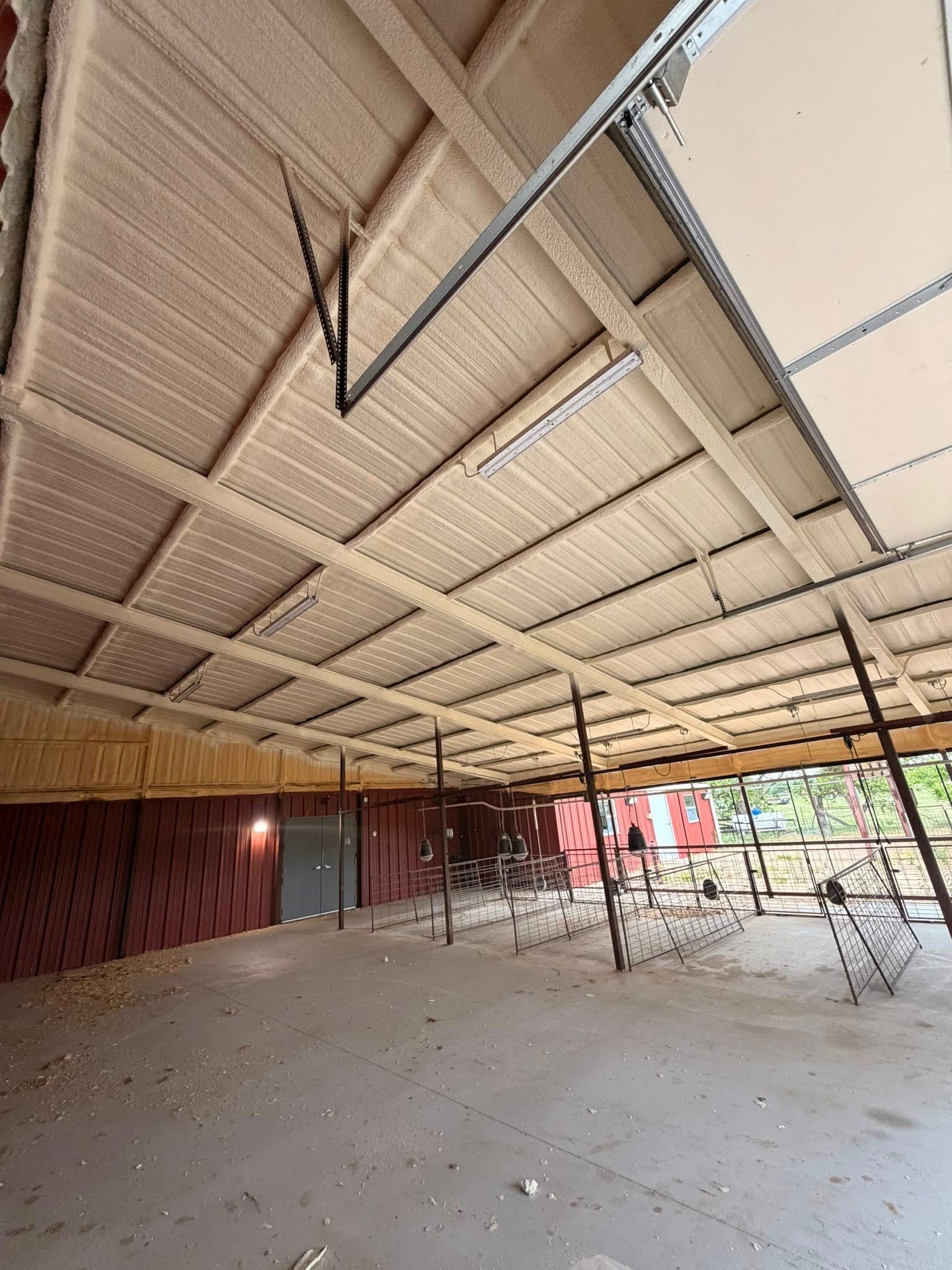 Open-sided warehouse with a metal roof, concrete floor, and construction materials inside