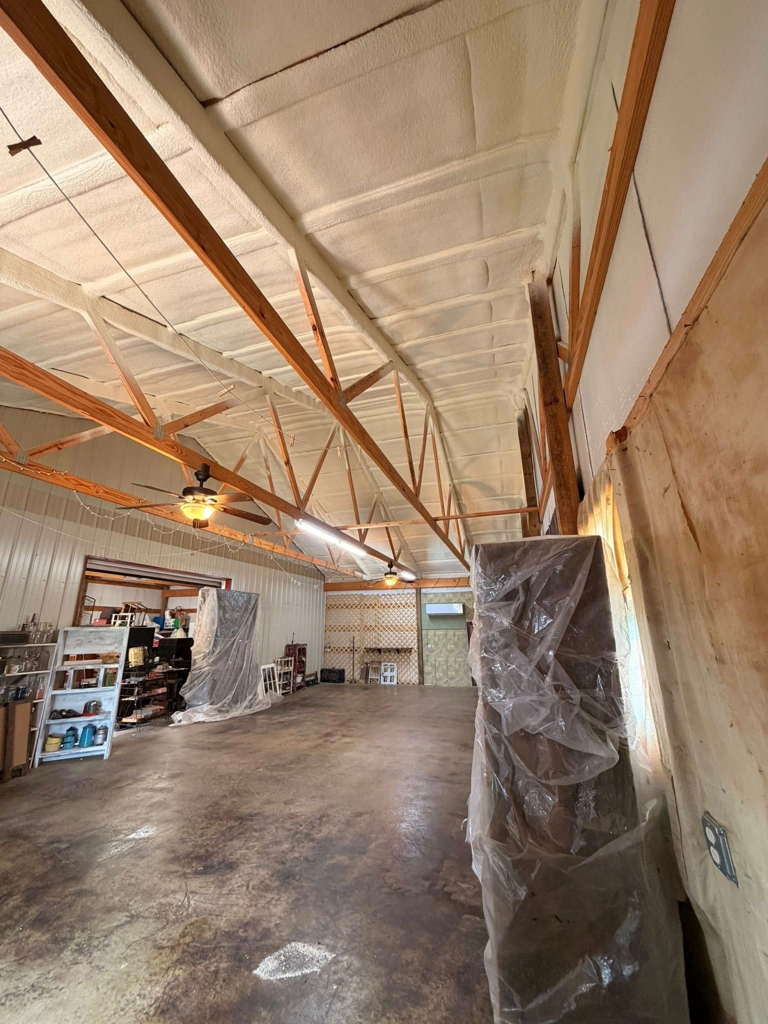 Empty warehouse interior with exposed ceiling beams, shelving, and a concrete floor