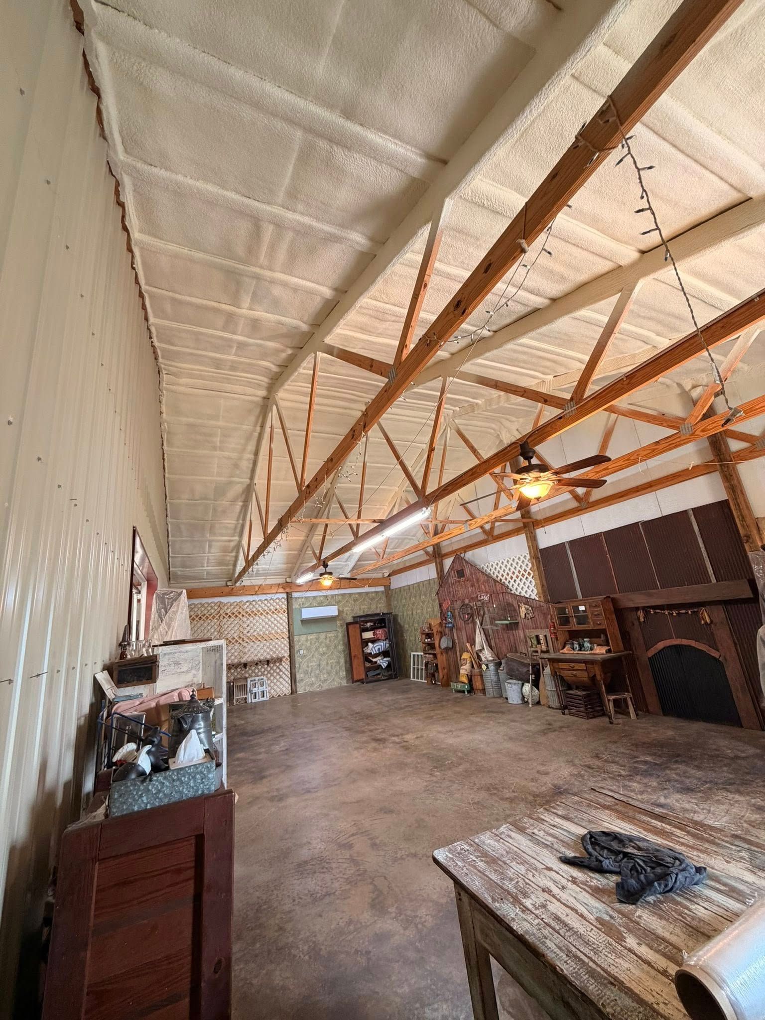 Rustic interior with exposed wooden beams, white ceiling, stone fireplace, and a wooden table in the foreground