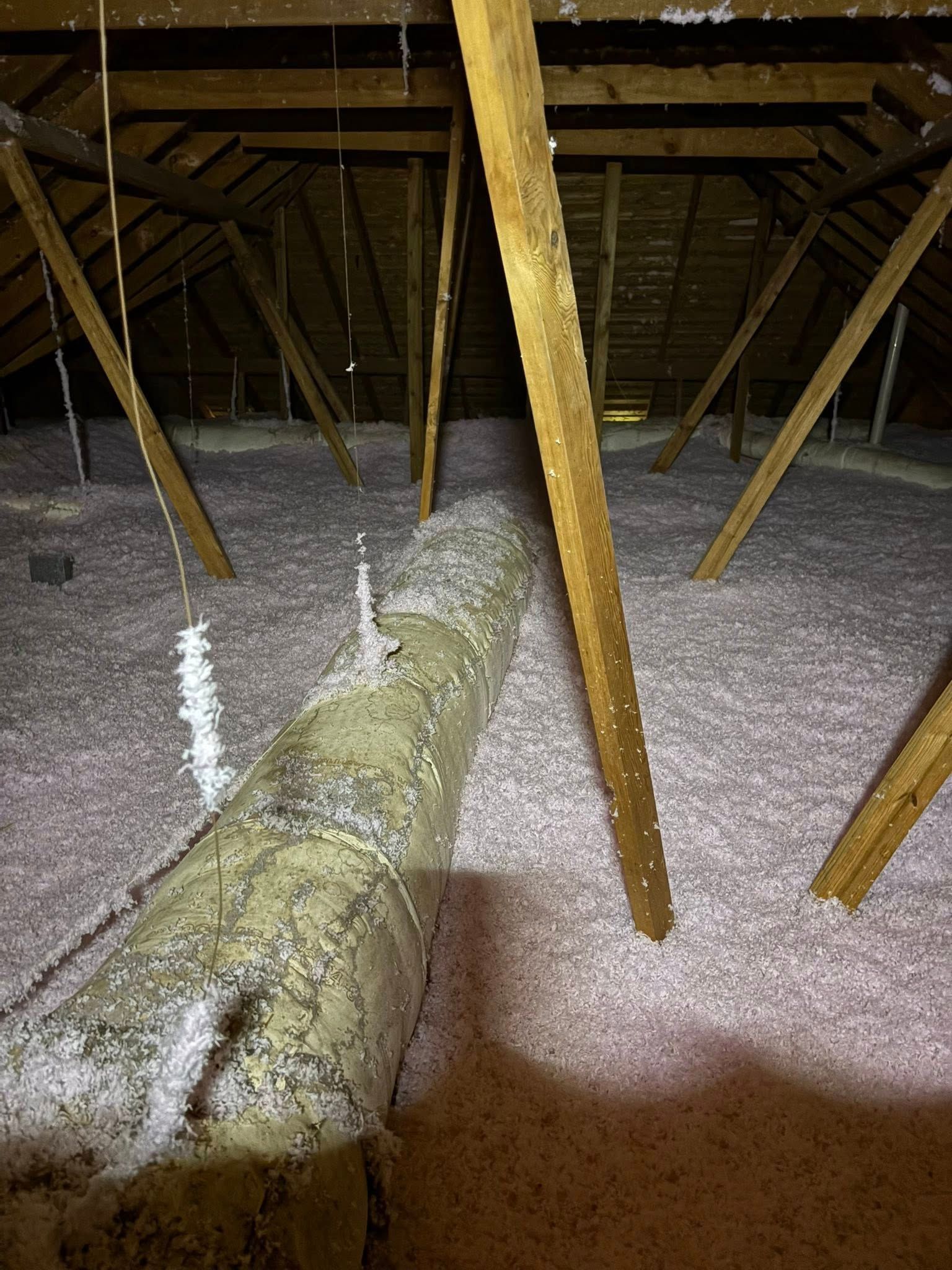 Inside a barn, muddy floor with metal posts and a plastic-covered object near the left wall.