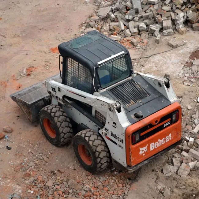 a bobcat tractor is sitting in a pile of rubble