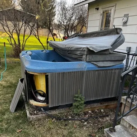 a hot tub is sitting in front of a house with the lid open .